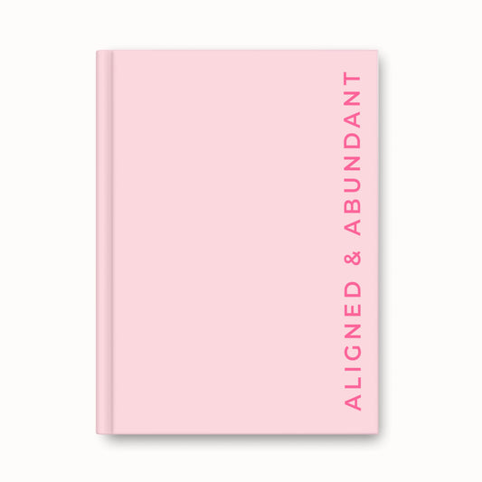 Pink hardback journal with “Aligned & Abundant” text in bold hot pink font