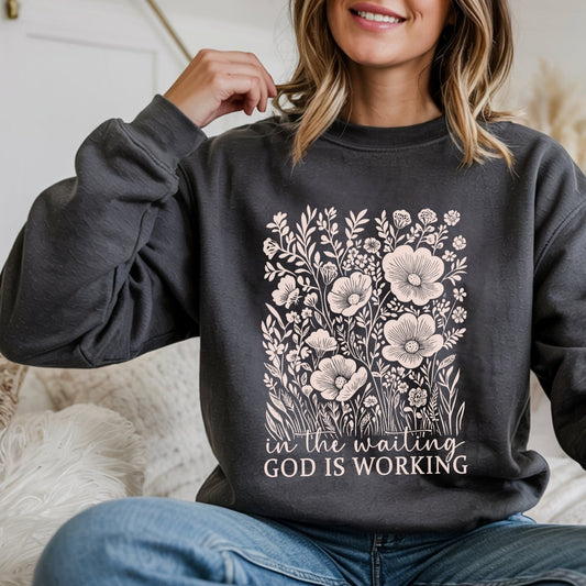 In The Waiting God Is Working dark heather sweatshirt worn by smiling blonde woman
