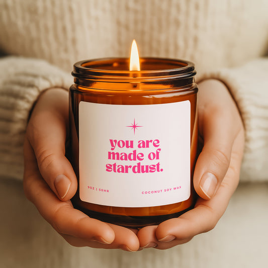 You are made of stardust faith candle with pink label and celestial design, hand poured coconut wax candle in a amber glass jar