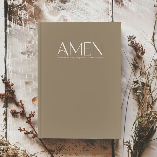 Hardcover AMEN journal with elegant typography and scripture on the cover, placed on a stylish desk.