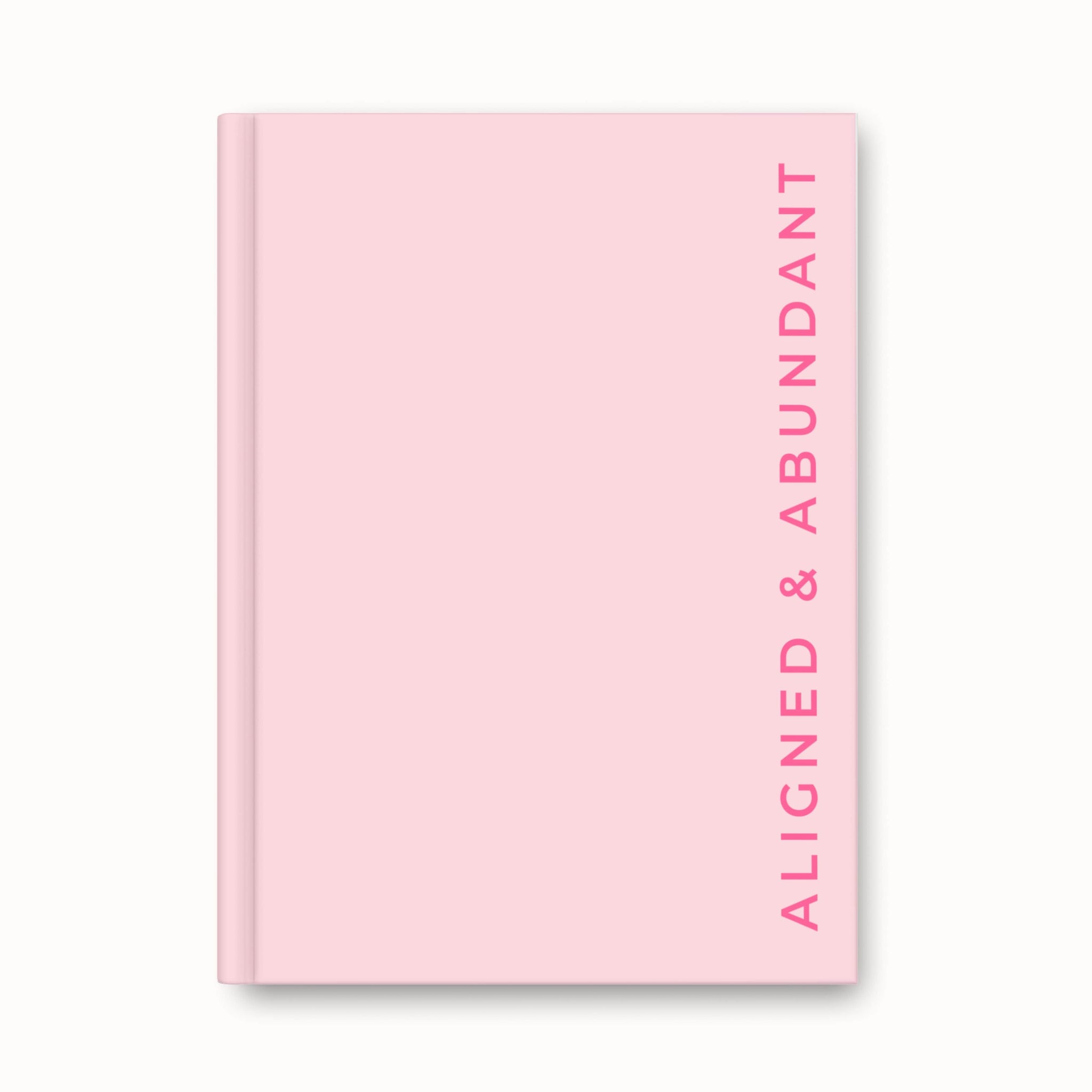 Pink hardback journal with “Aligned & Abundant” text in bold hot pink font