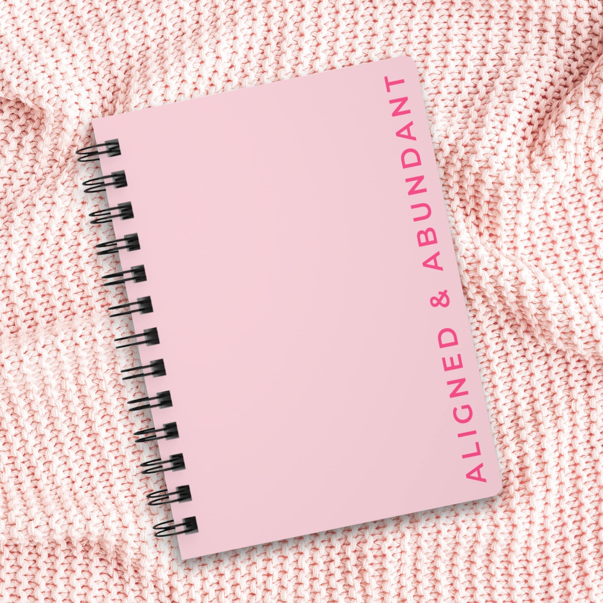 Pink notebook with 'Aligned & Abundant' text on a textured pink background