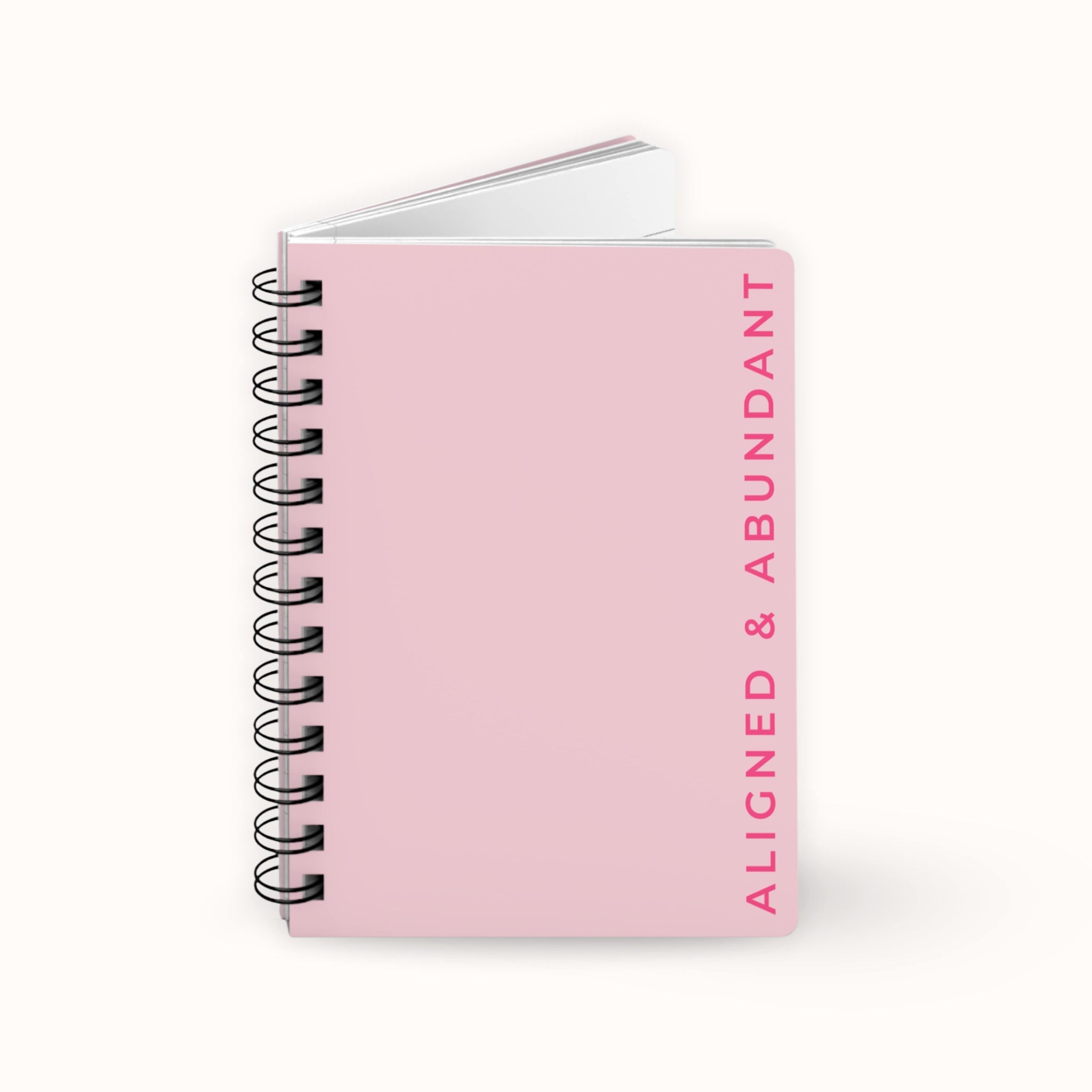 Pink spiritual notebook with 'Aligned & Abundant' text on a white background