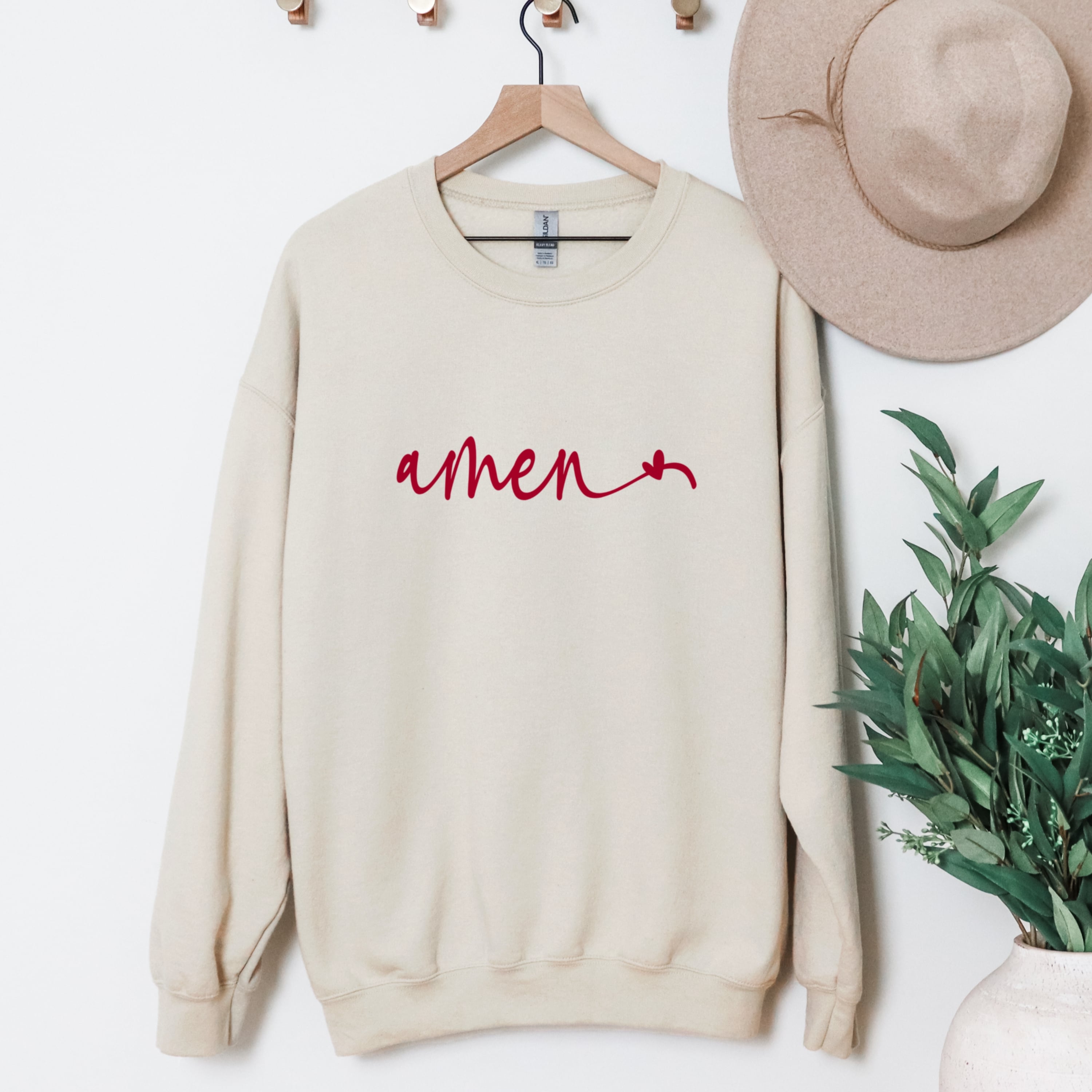 Beige Amen sweatshirt with heart detail hanging display - neutral minimalist Christian crewneck clothing