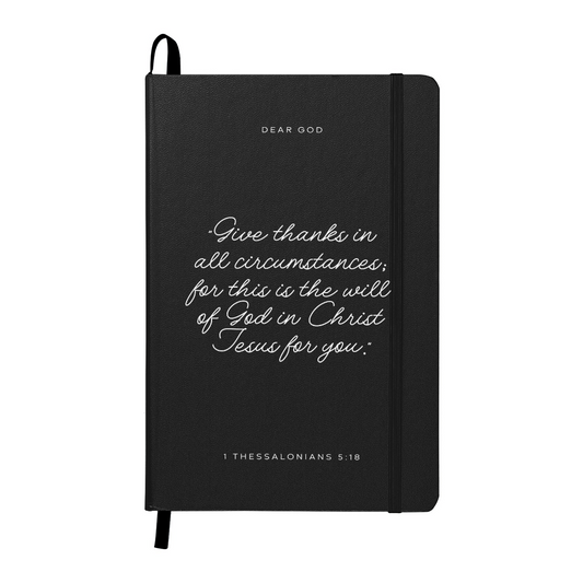 Black prayer journal with ‘1 Thessalonians 5:18’ printed on the cover, designed for faith-based reflections and gratitude journaling.