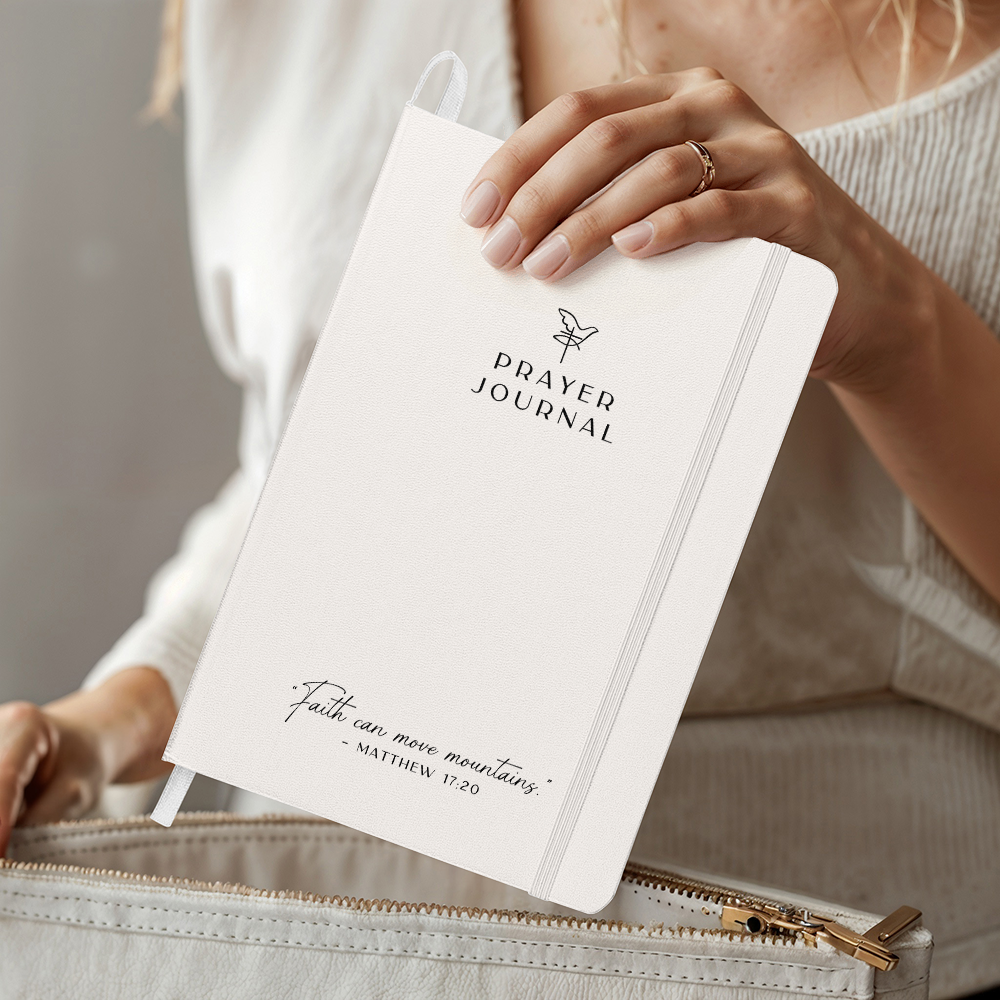 Beautiful prayer journal with the bible quote 'Faith can move mountains' on the front being held up to show the front cover.