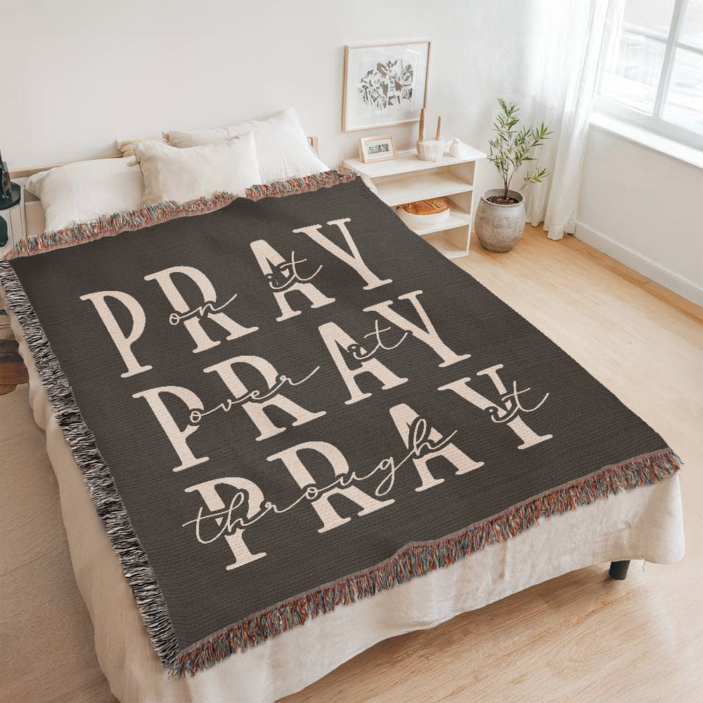 A beautifully textured cotton blanket with an embroidered faith-filled quote, draped over a bed, creating a cozy, peaceful atmosphere.