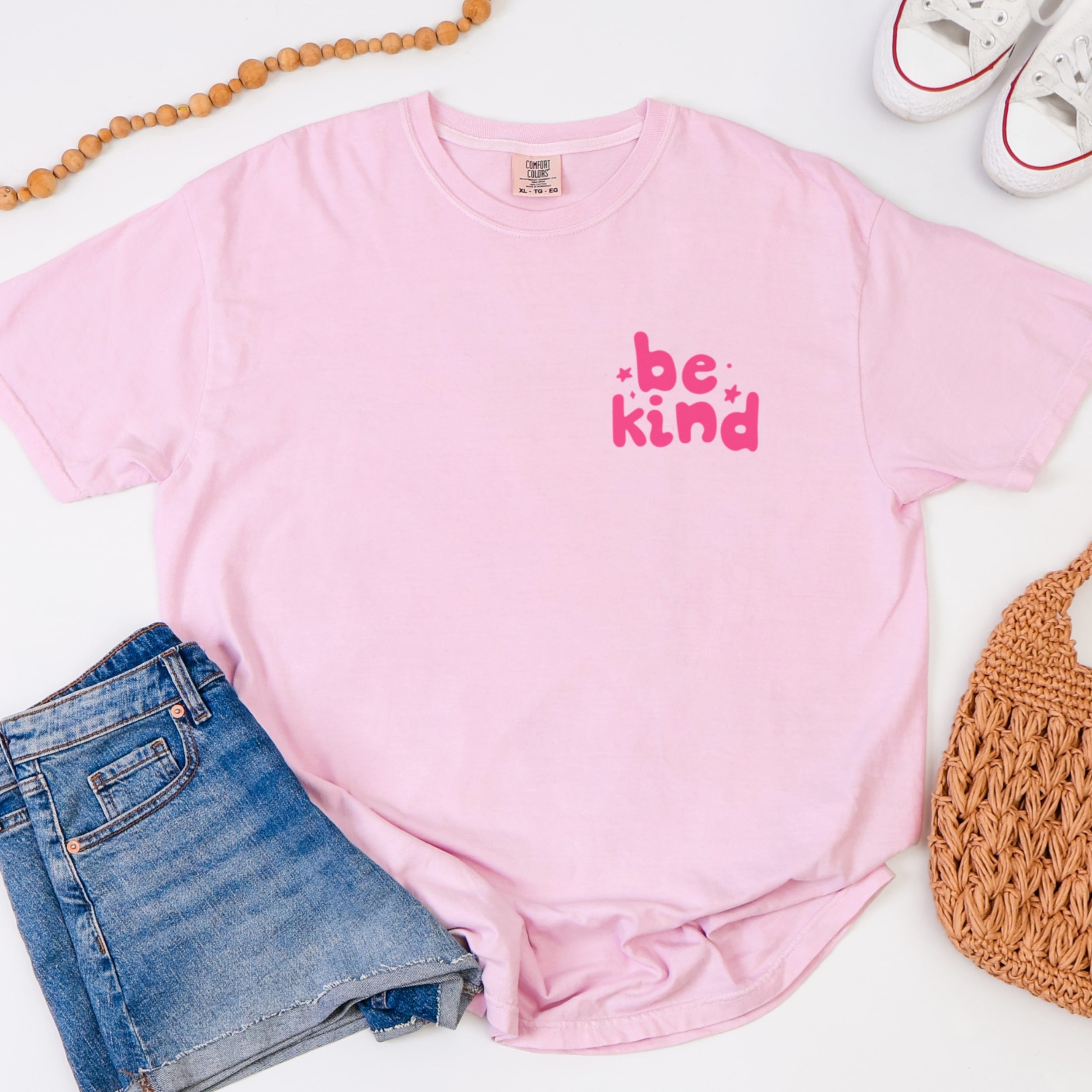 Close up of Be Kind inspirational tshirt design in hot pink on blossom pink cotton fabric