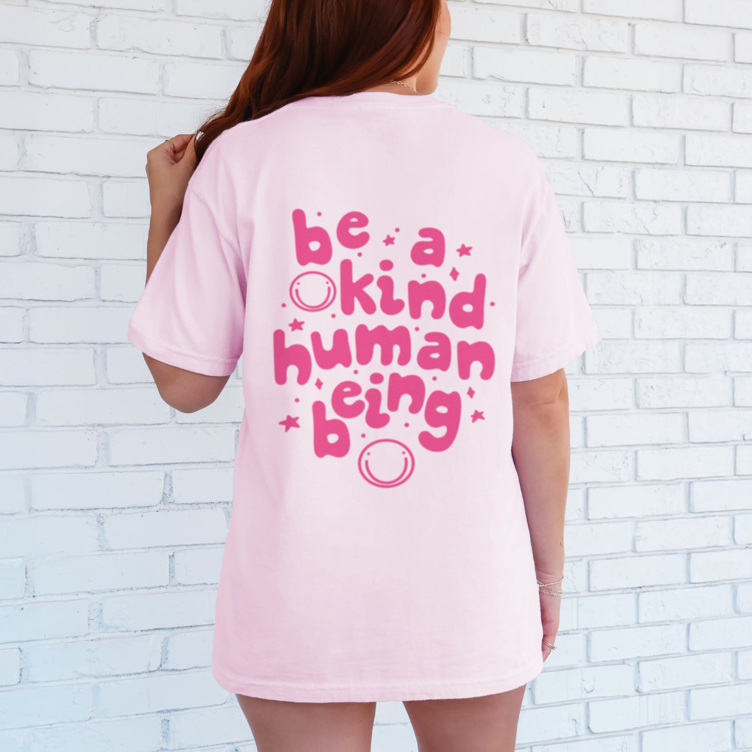 Back view of Be A Kind Human Being tshirt in blossom pink with hot pink lettering, oversized fit kindness message shirt