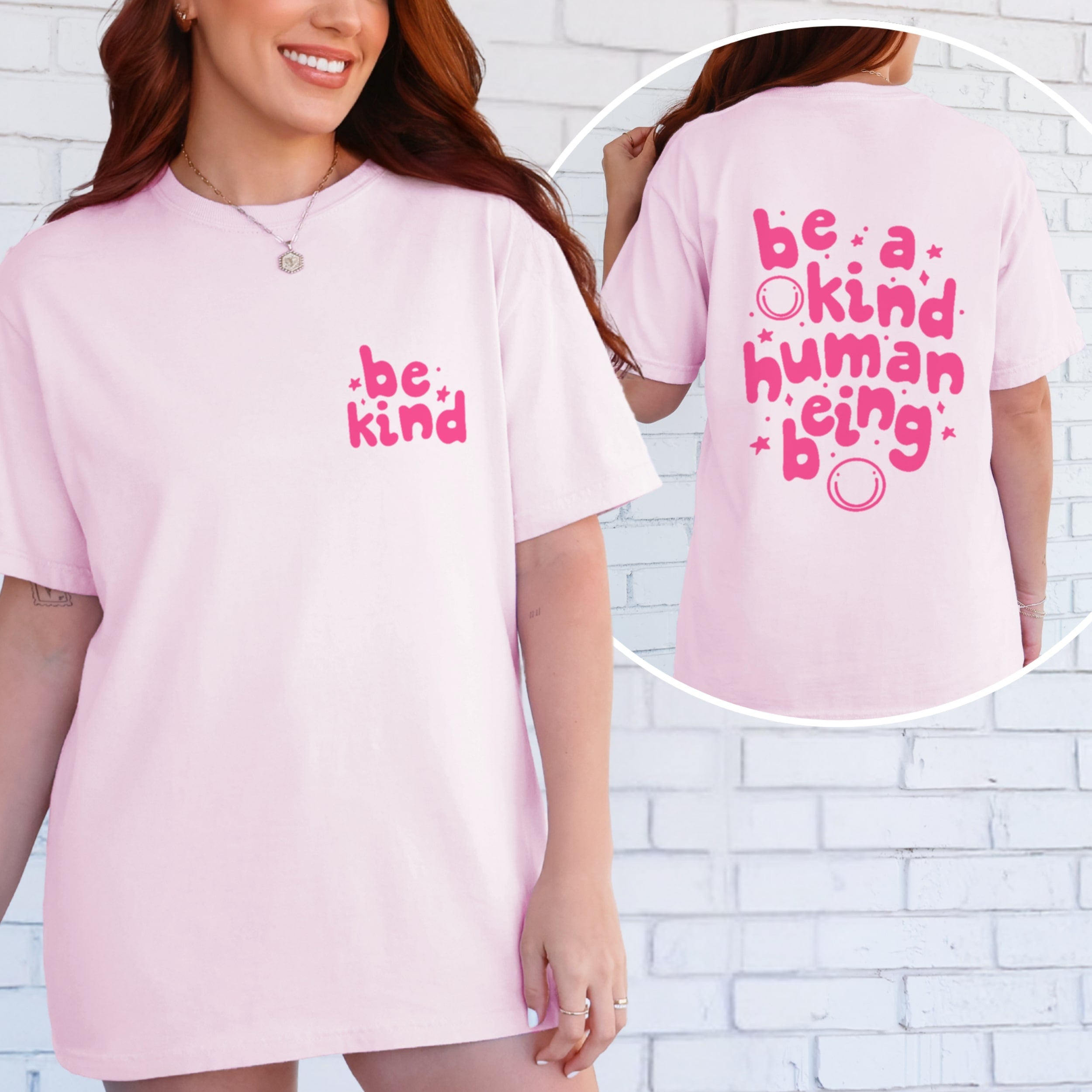 Woman wearing light pink Be Kind tshirt with small hot pink text on front chest, and 'Be A Kind Human Being' on the back.