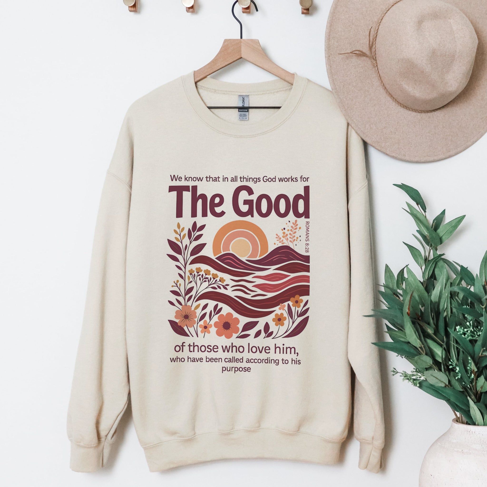 God Works For The Good Romans 8:28 beige sweatshirt hanging display - boho landscape Christian crewneck clothing