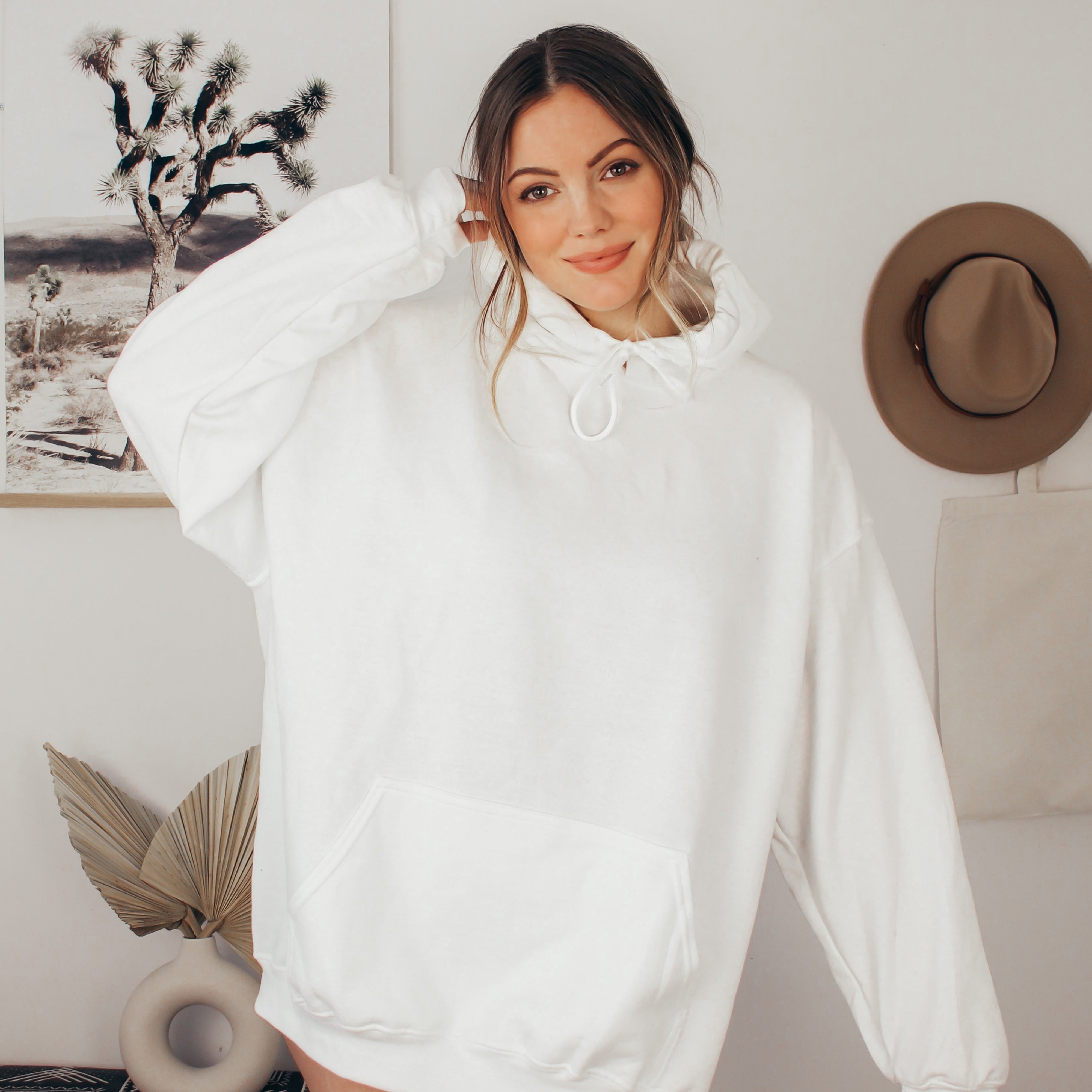 Woman wearing a white faith hoodie in a casual indoor setting with decor elements.