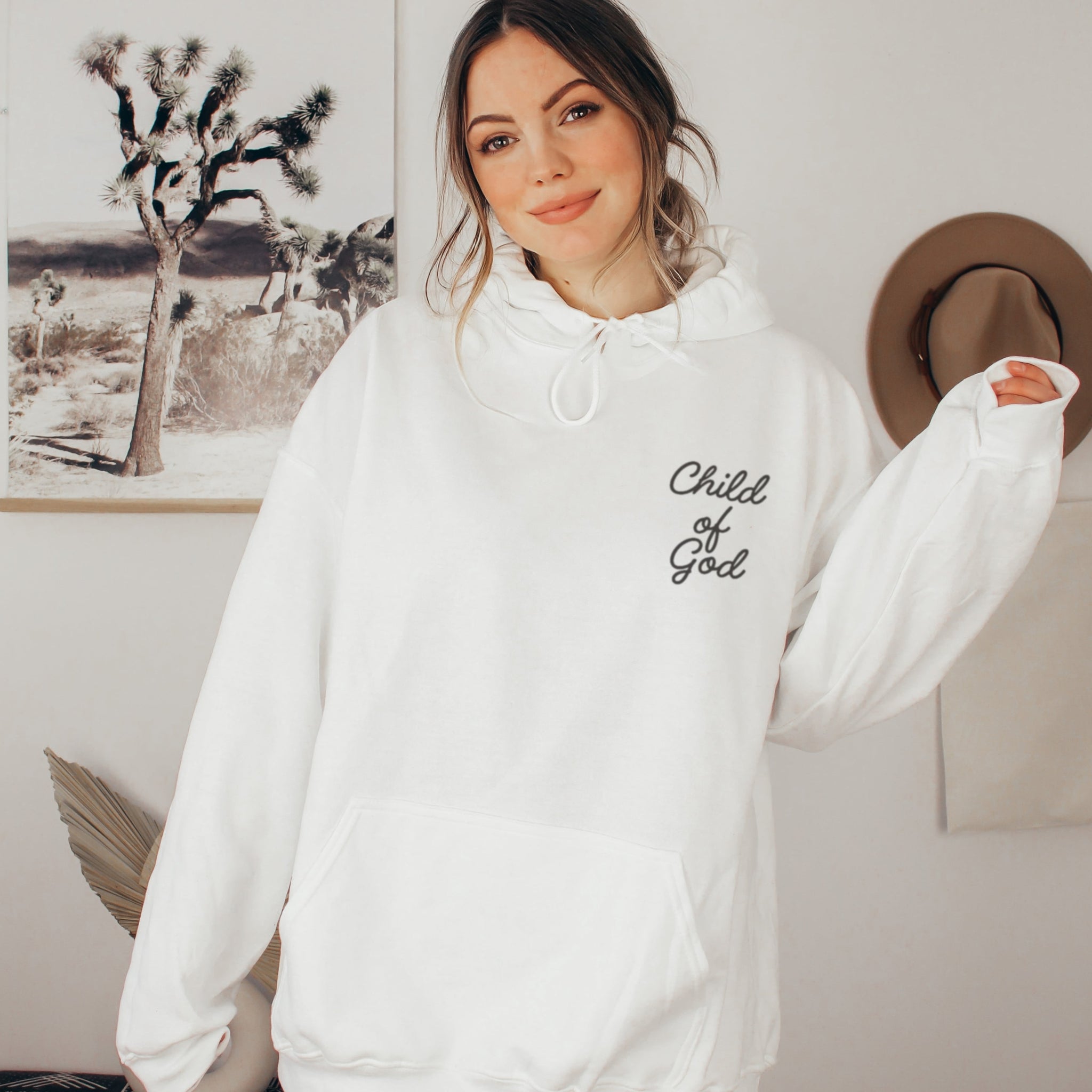 Woman wearing white Child of God hoodie, minimalist Christian faith sweatshirt for women with script lettering