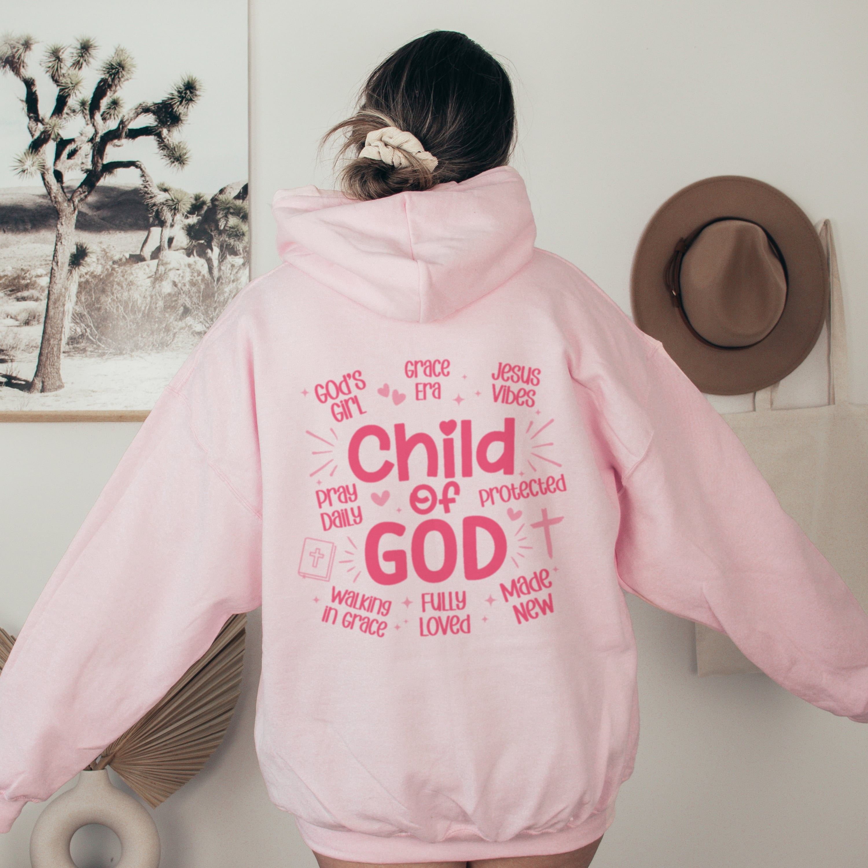 Woman wearing pink Child of God hoodie, Christian faith-based sweatshirt for women with cute text