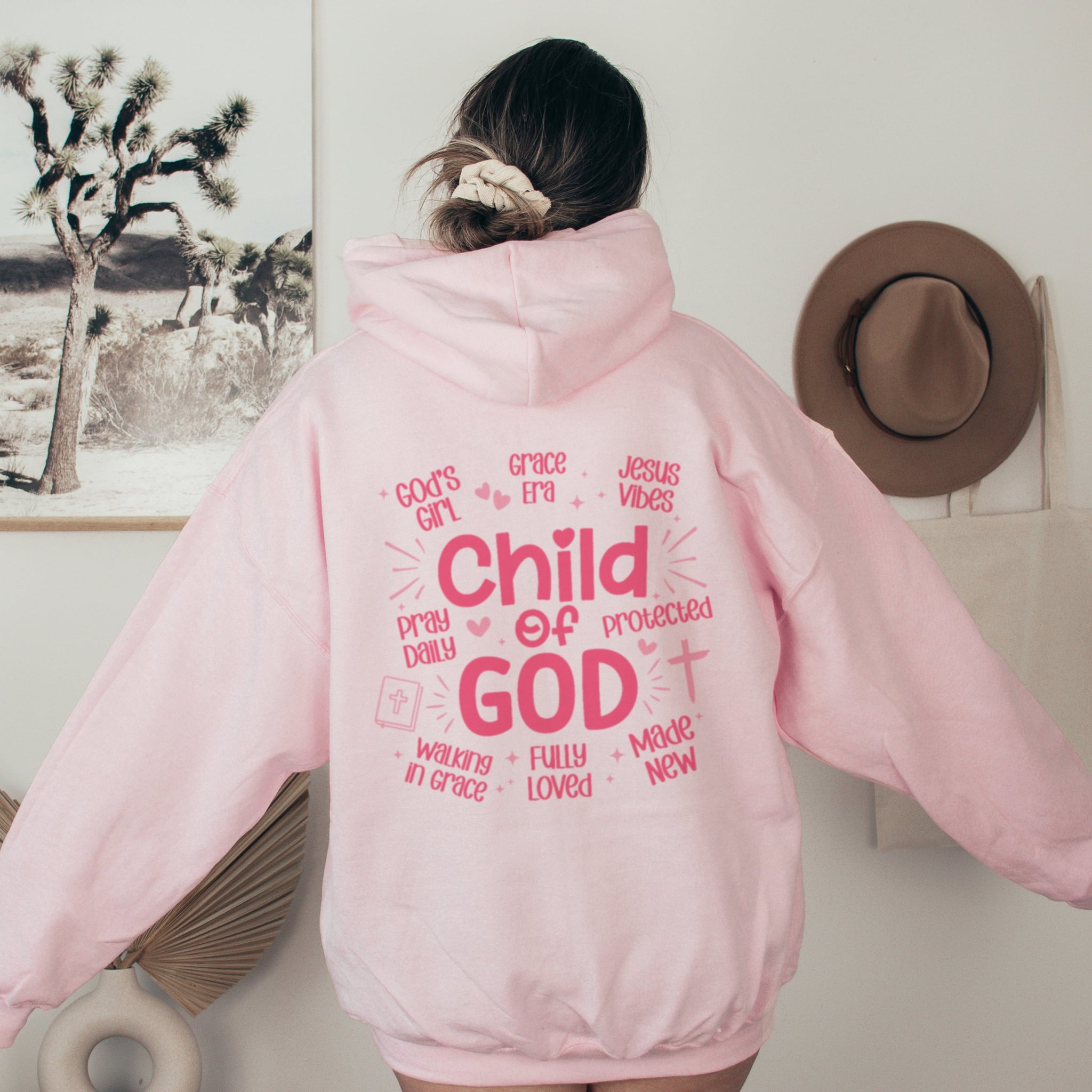 Woman wearing pink Child of God hoodie, Christian faith-based sweatshirt for women with cute text
