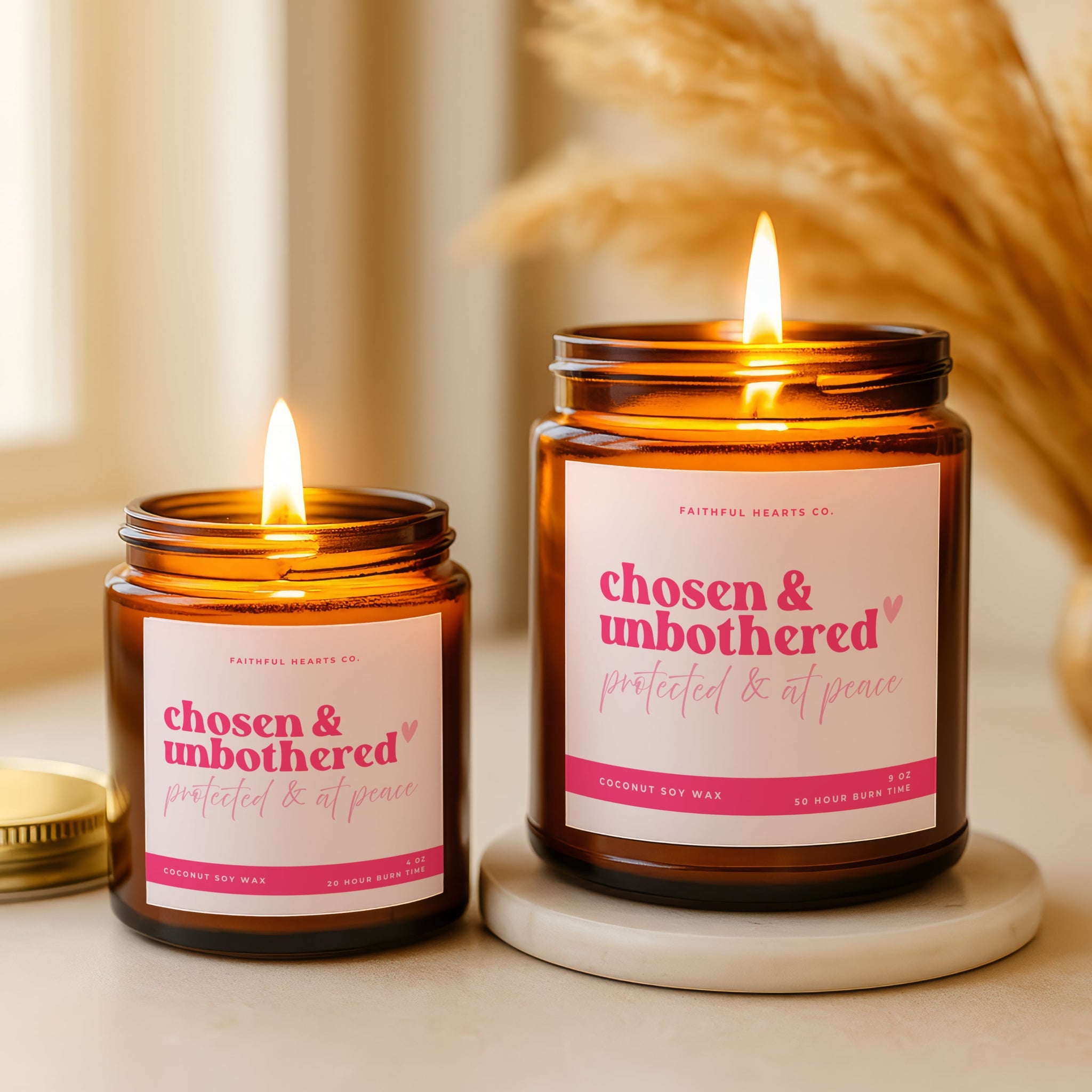 Two lit candles in amber jars with 'chosen & unbothered' labels on a neutral background.