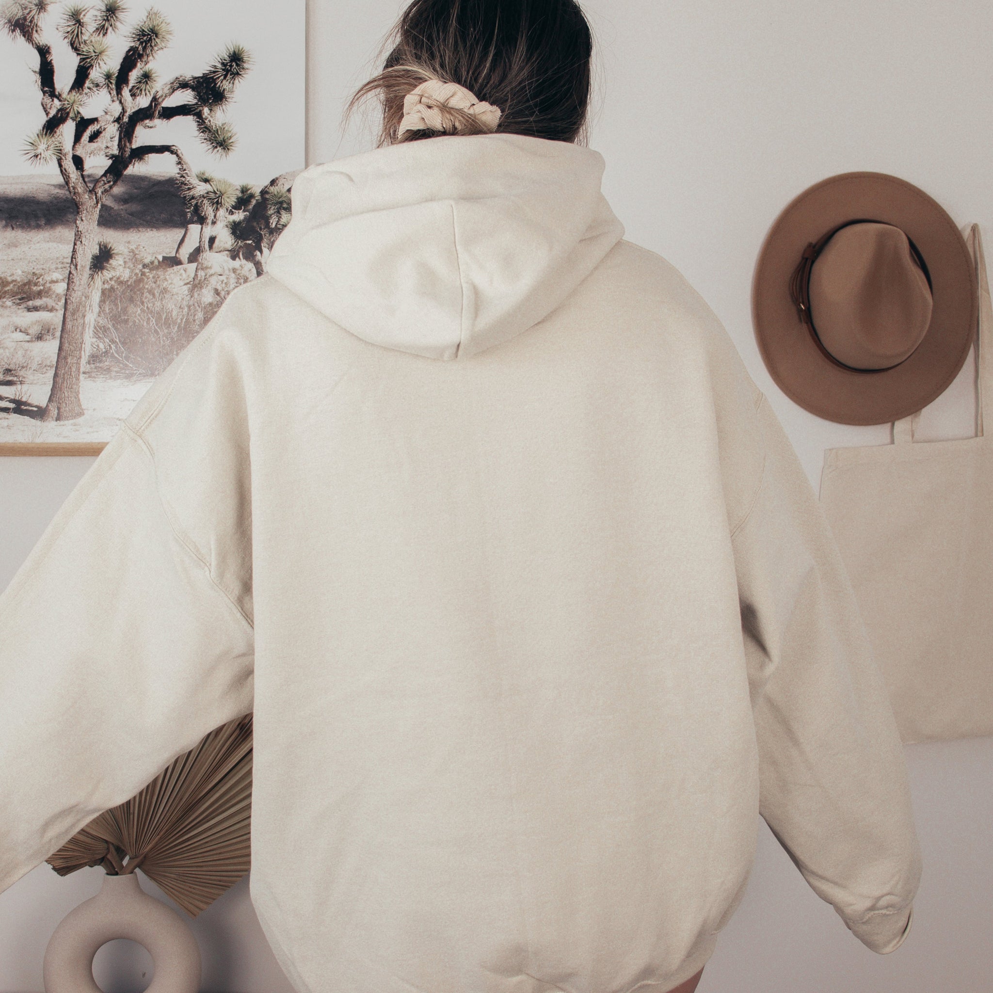 Person wearing a beige hoodie with a neutral background