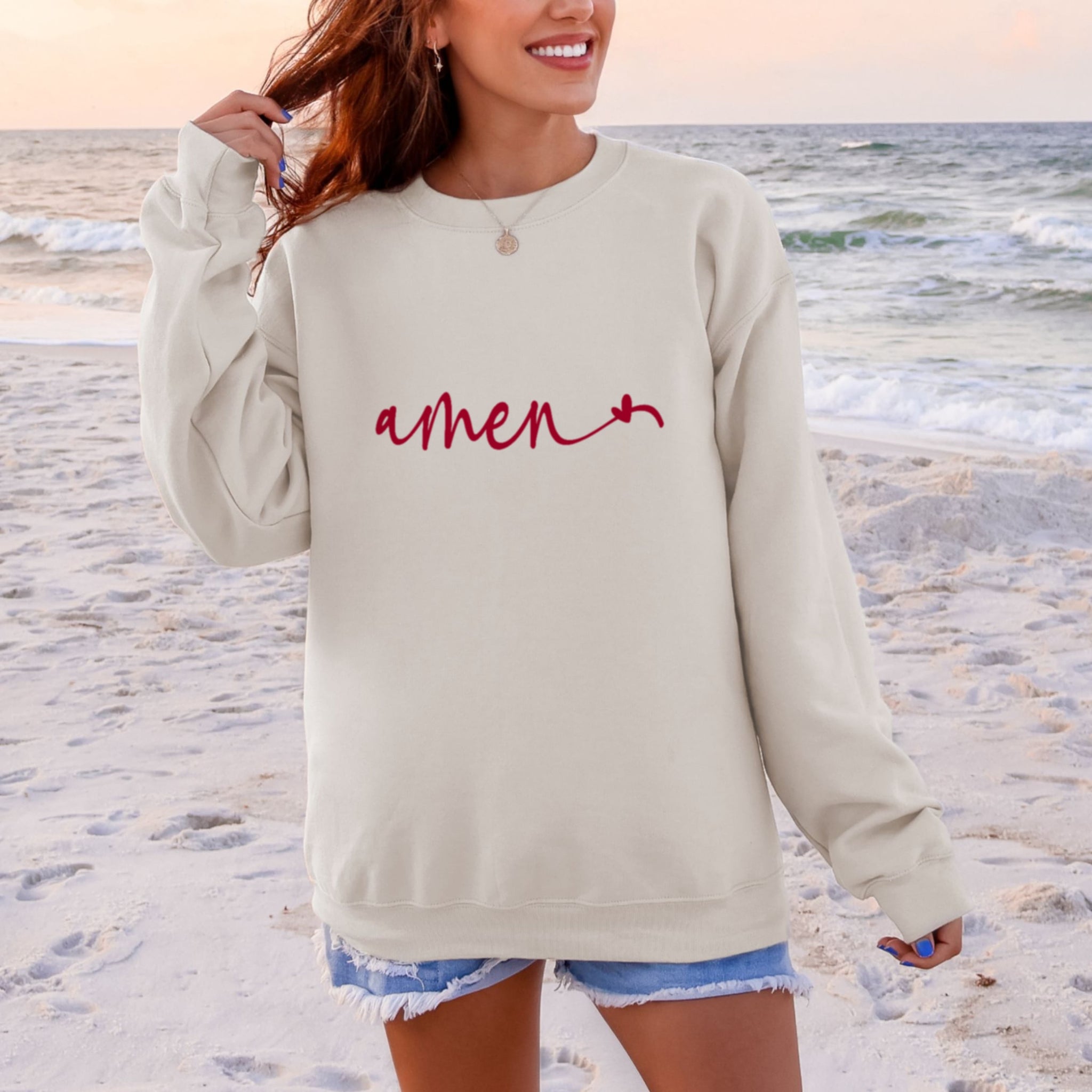 Woman wearing cream beige Amen sweatshirt with heart detail and jeans - minimalist Christian crewneck for women