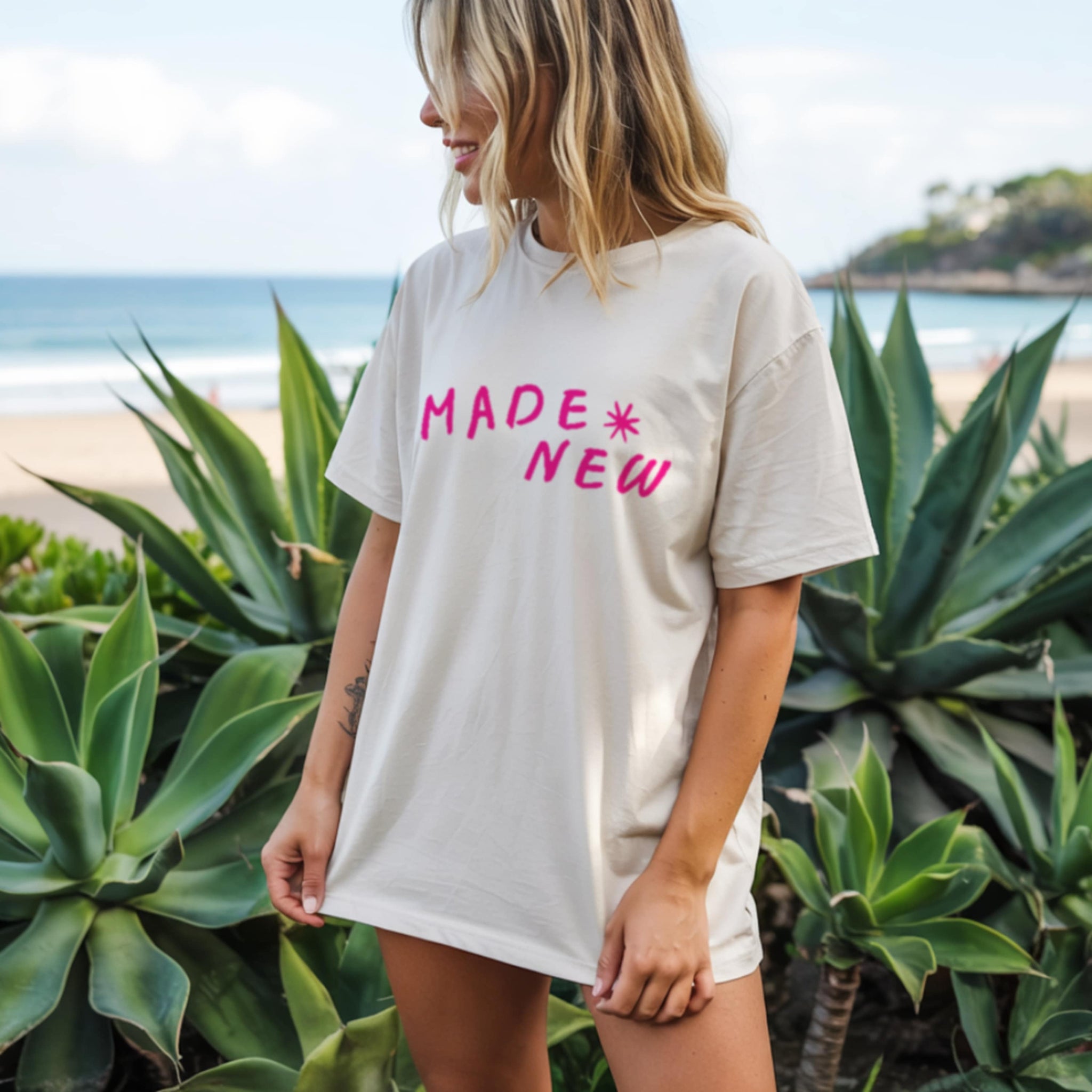 Woman wearing Made New ivory Christian t-shirt on a beach