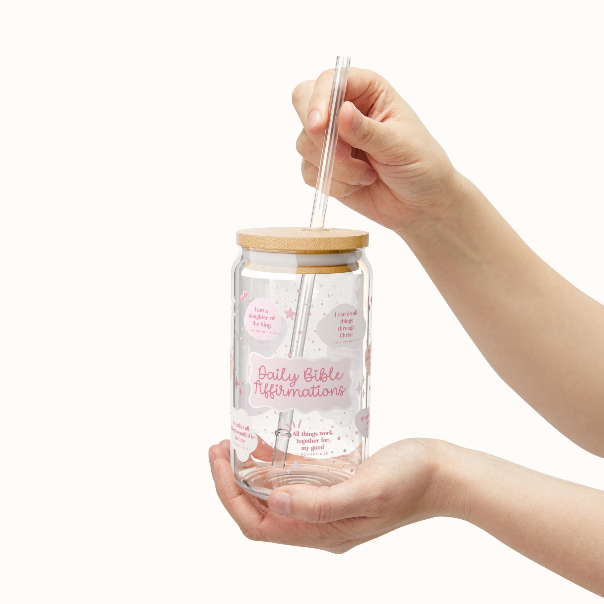 Cute Daily Bible affirmations Glass jar with wooden lid and straw, held by a hand on a white background