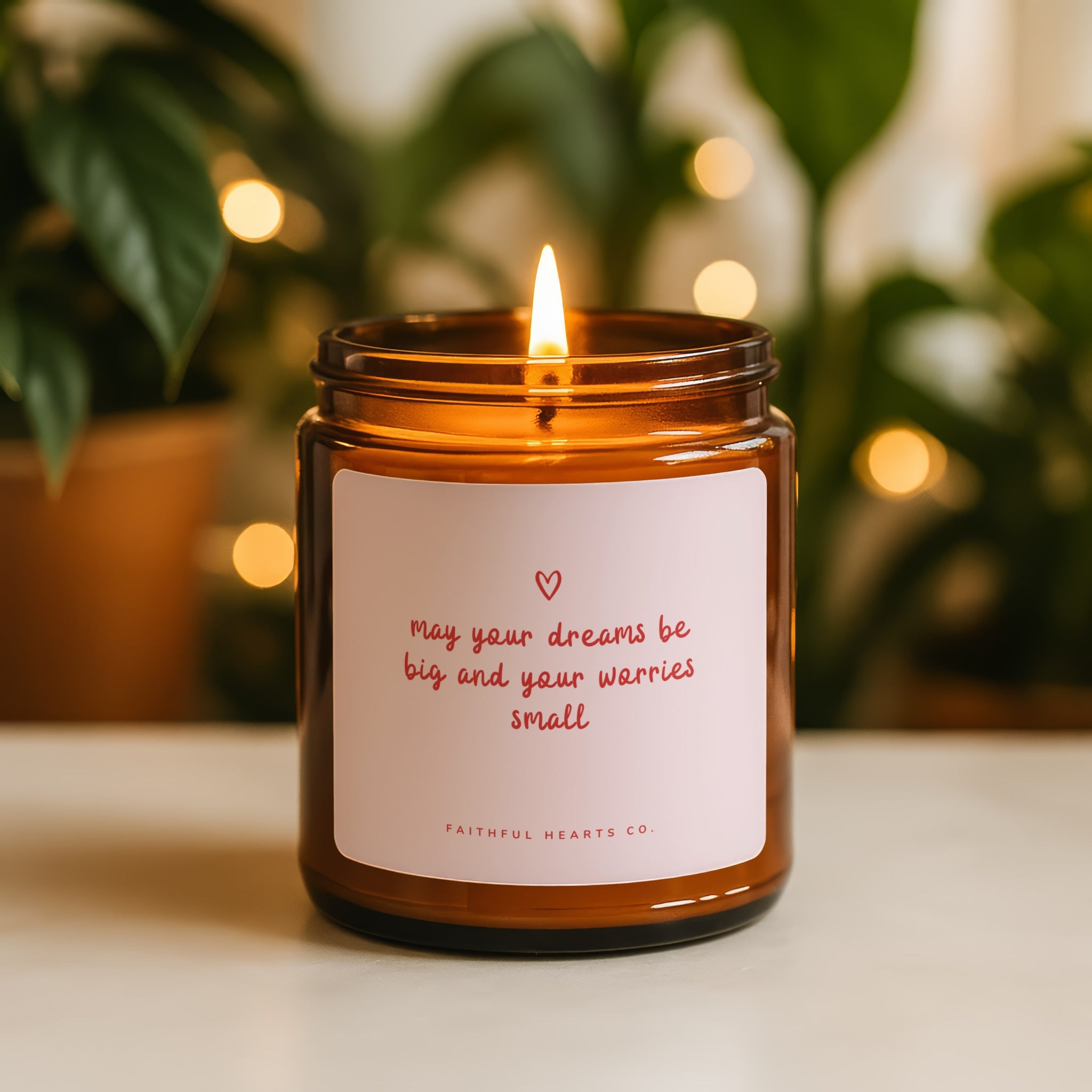 Candle in an amber jar with a motivational label, surrounded by plants and soft lighting.