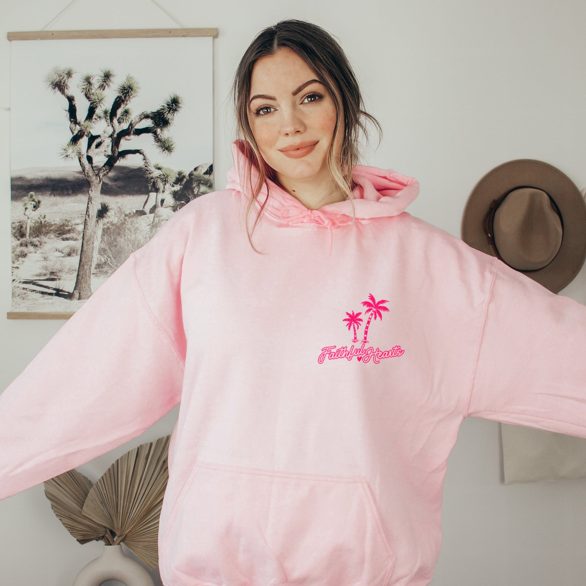 Faithful Hearts logo on pink hoodie with palm trees, faith-based clothing brand detail