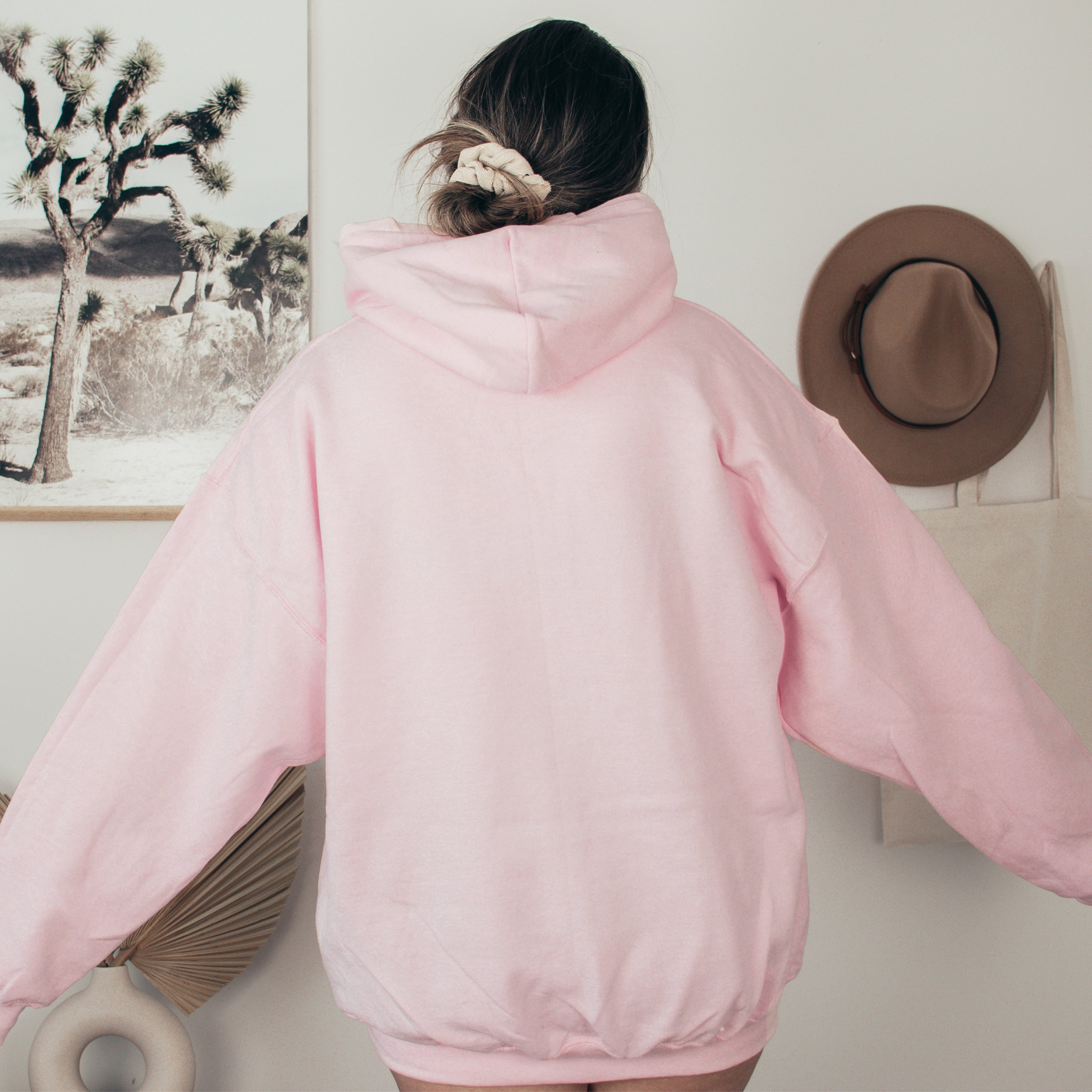 Person wearing a pink hoodie with a hat and fan in the background