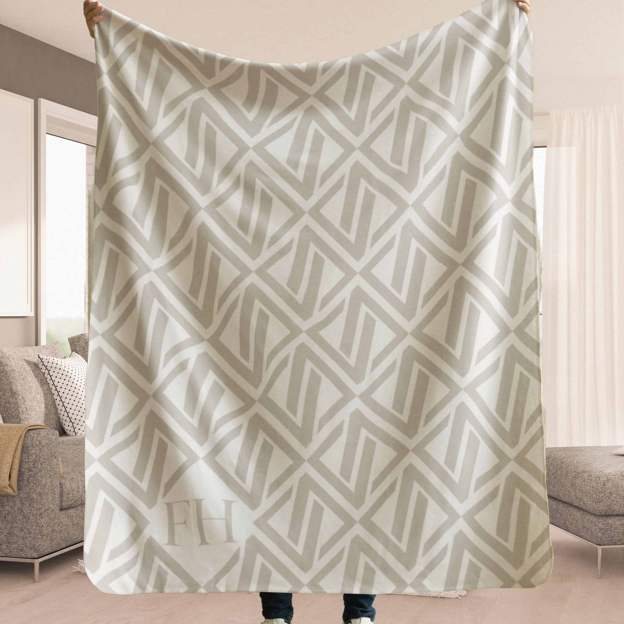 luxury sherpa blanket with a netural colored geometric pattern with the faithful hearts logo in the corner being held up by someone to show how large it is