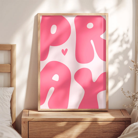 Pink pray wall art print with bubble letters and heart in wooden frame on dresser