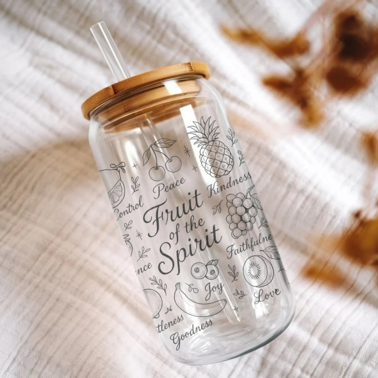 Christian Fruit of the Spirit sipper glass featuring Galatians 5:22-23 with hand-drawn fruit illustrations, bamboo lid and glass straw on wooden surface