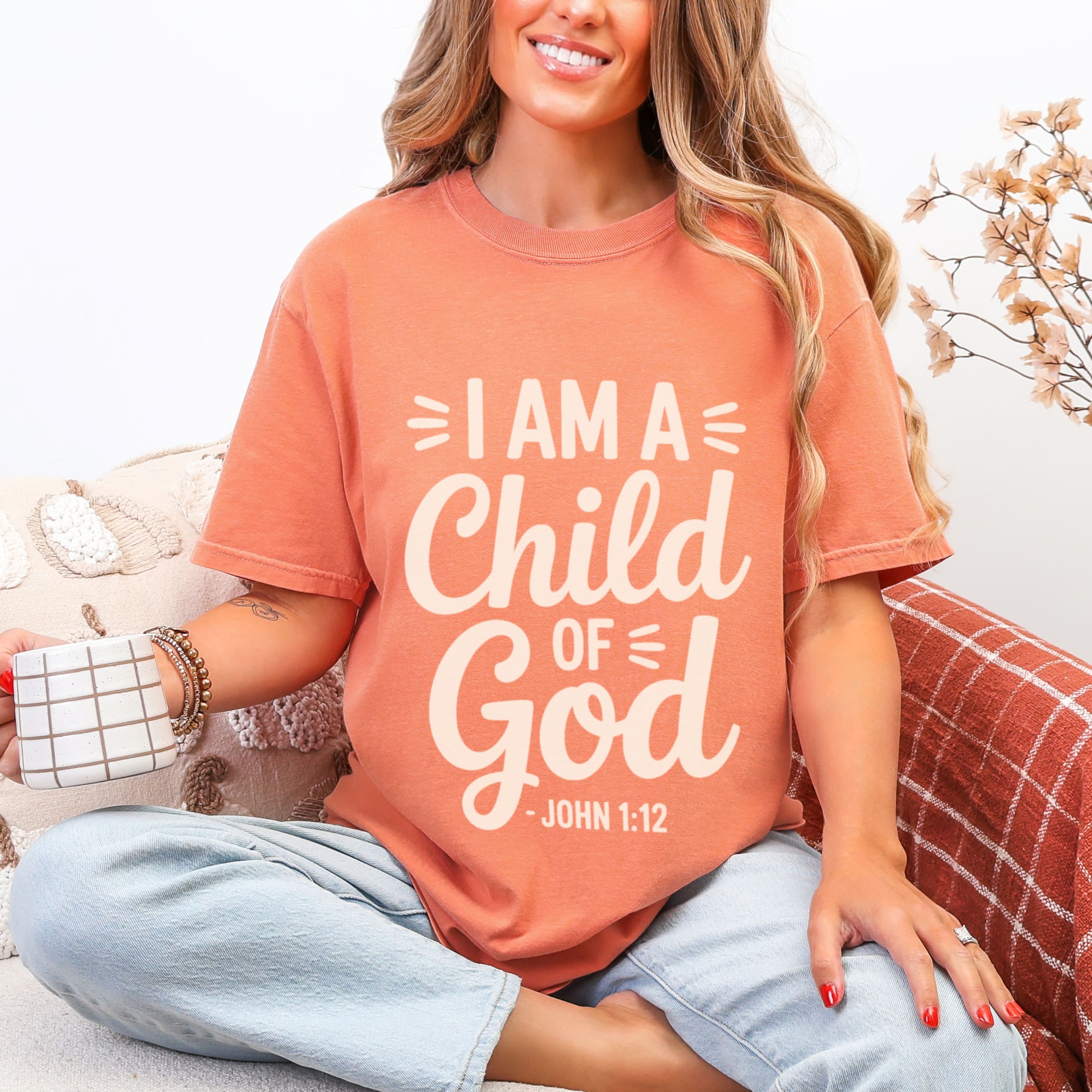 Woman wearing terracotta I Am A Child Of God tshirt with cream lettering and John 1:12, faith-based identity graphic tee
