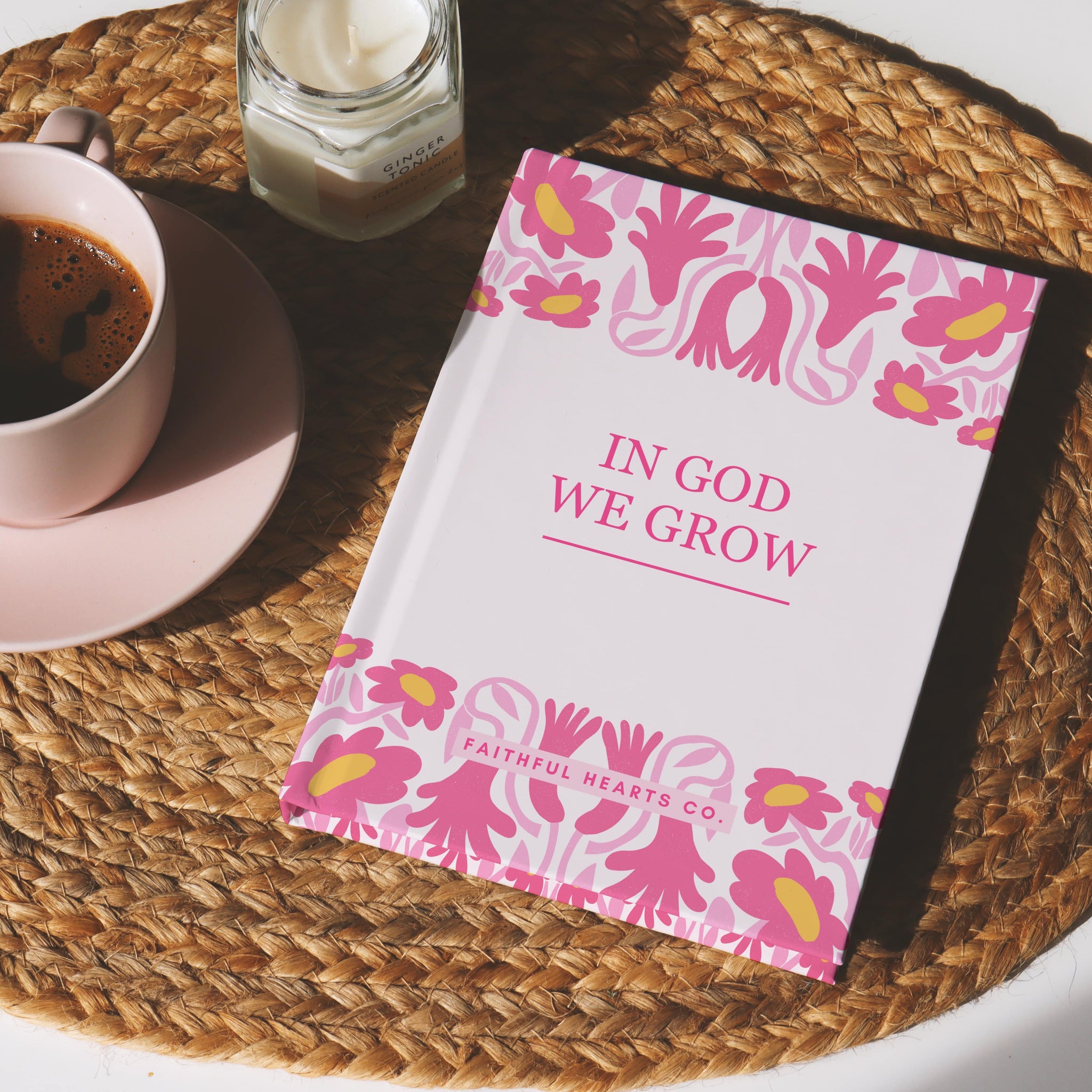Book titled 'In God We Grow' with floral design on a woven tray with a cup of coffee.