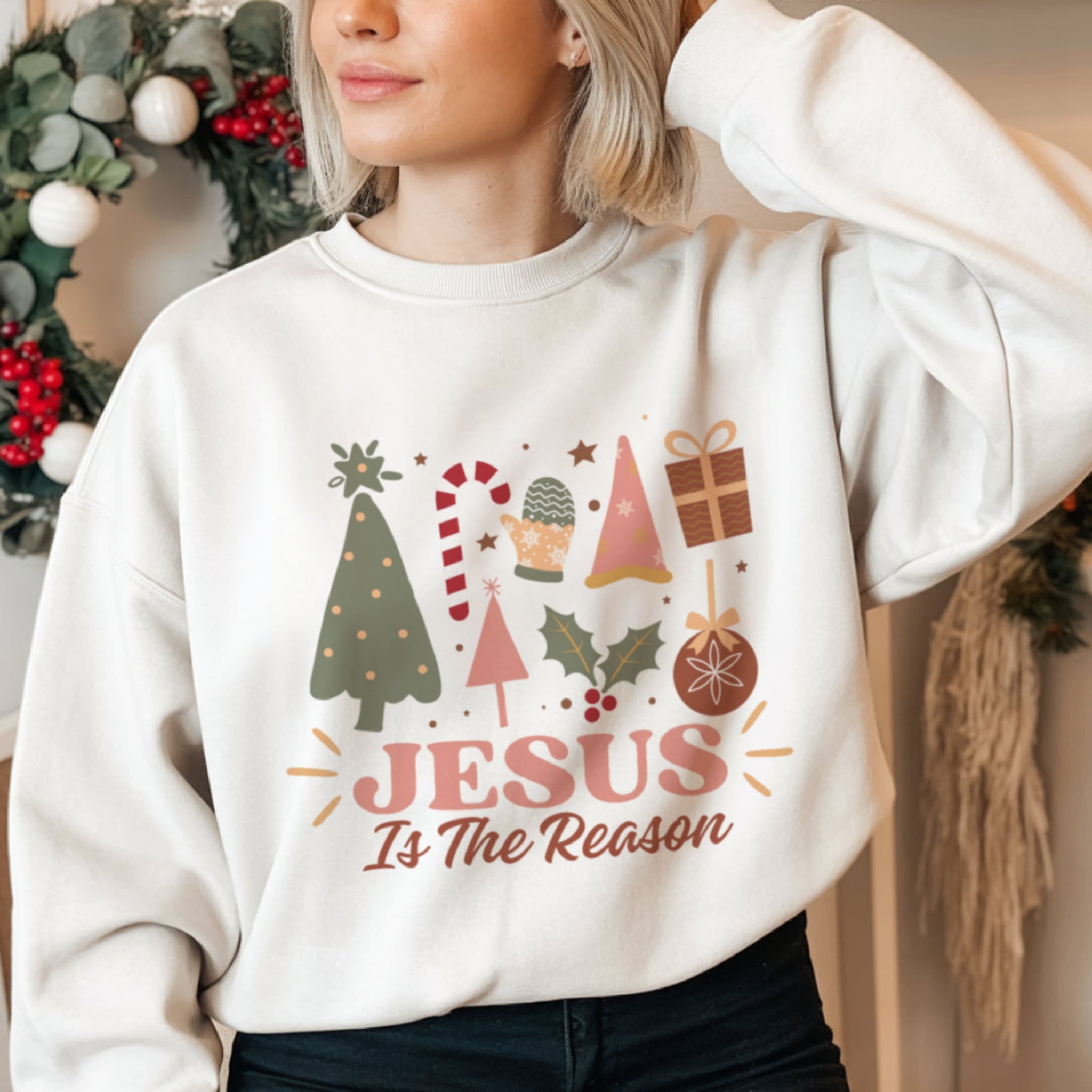 Woman wearing Jesus Is The Reason white Christmas crewneck sweatshirt, cozy Christian xmas outfit for women