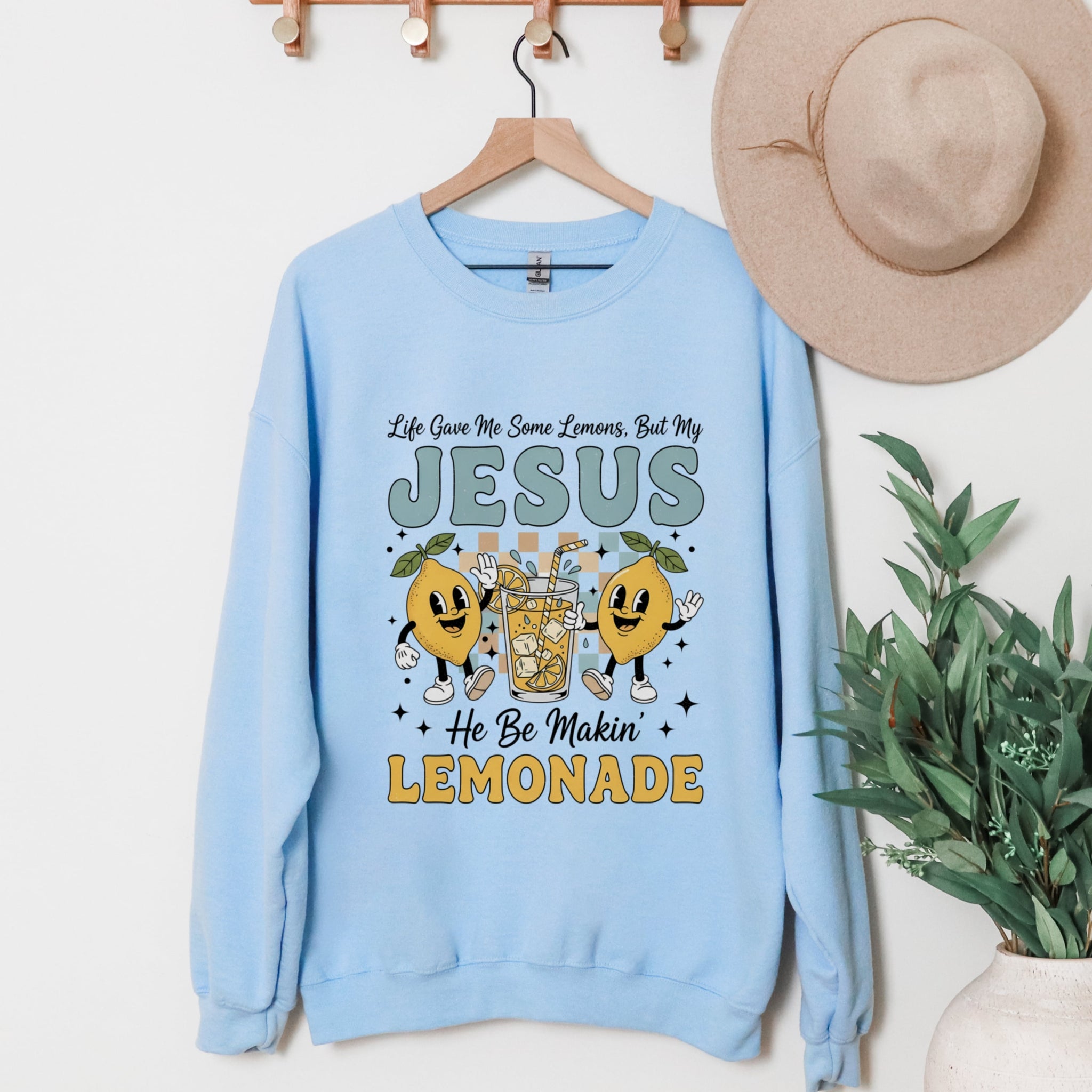 Light blue Jesus Making Lemonade sweatshirt hanging display with cute Christian crewneck with lemon characters