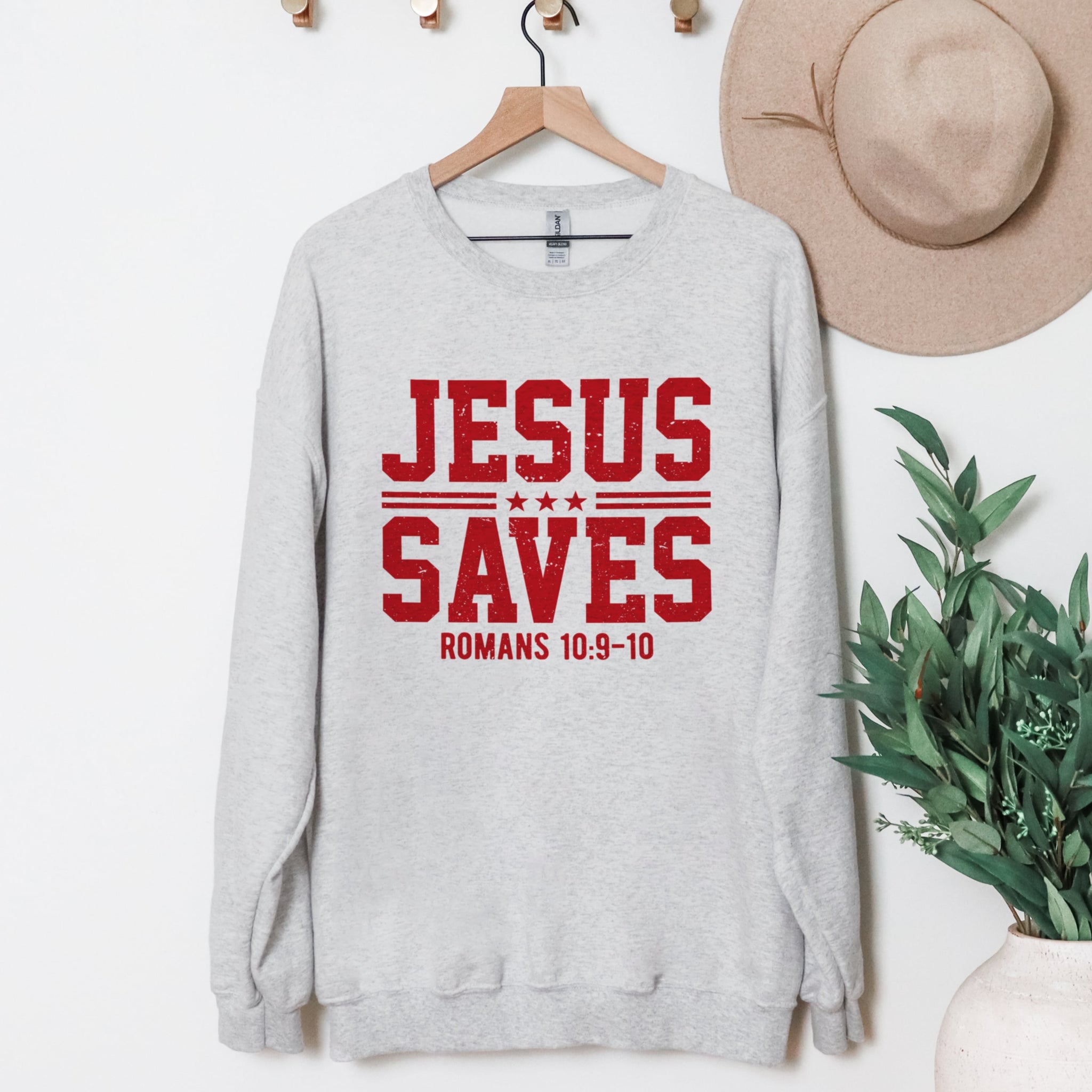 Jesus Saves ash grey sweatshirt showing vintage athletic typography, Romans Bible verse.