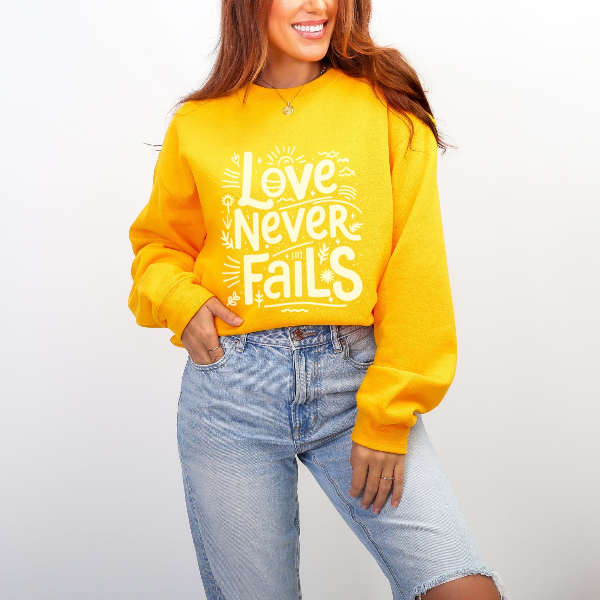Yellow Love Never Fails sweatshirt with 1 Corinthians 13:8 message styled with jeans - cheerful Christian faith crewneck