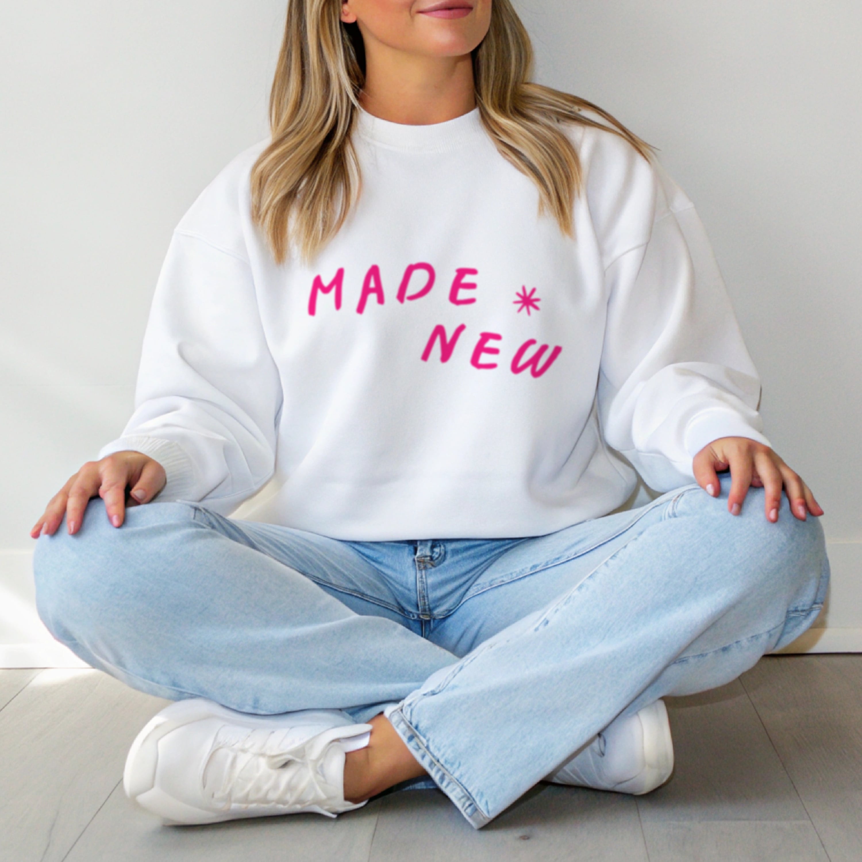 Woman wearing Made New faith crewneck sweatshirt styled with jeans, cozy Christian apparel for women