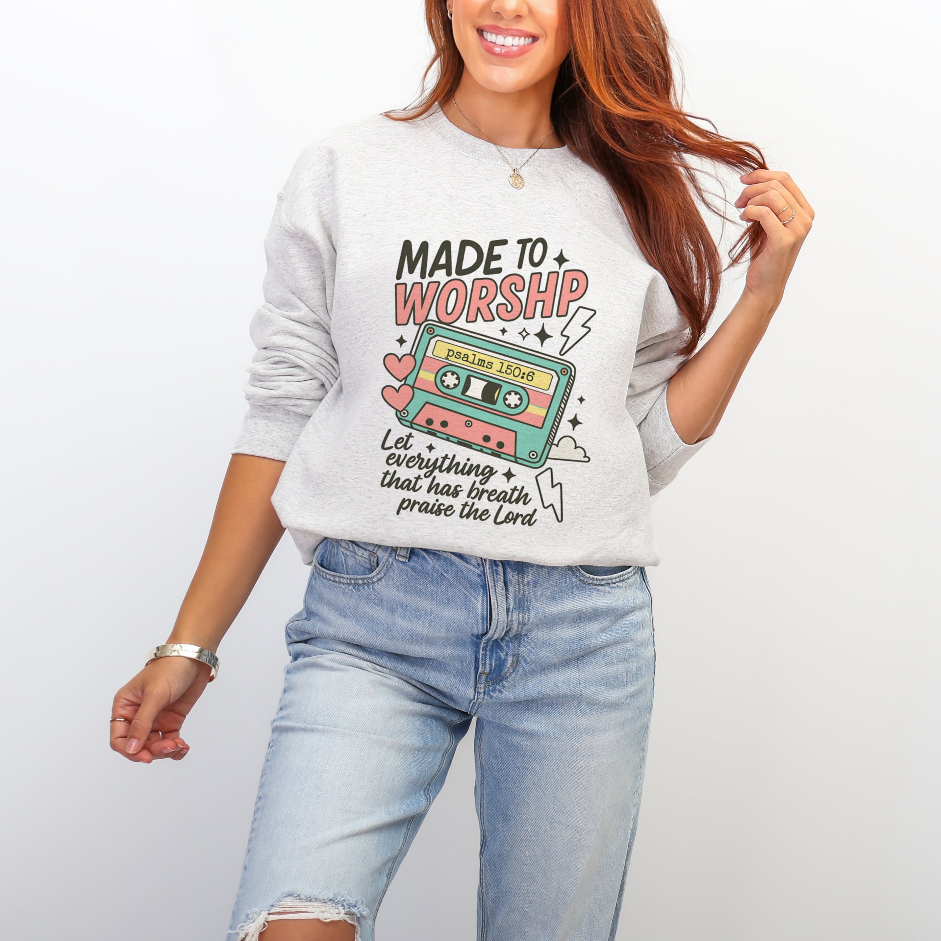 Woman wearing ash grey Made To Worship sweatshirt with retro cassette tape Psalm 150:6 design - fun Christian crewneck for women