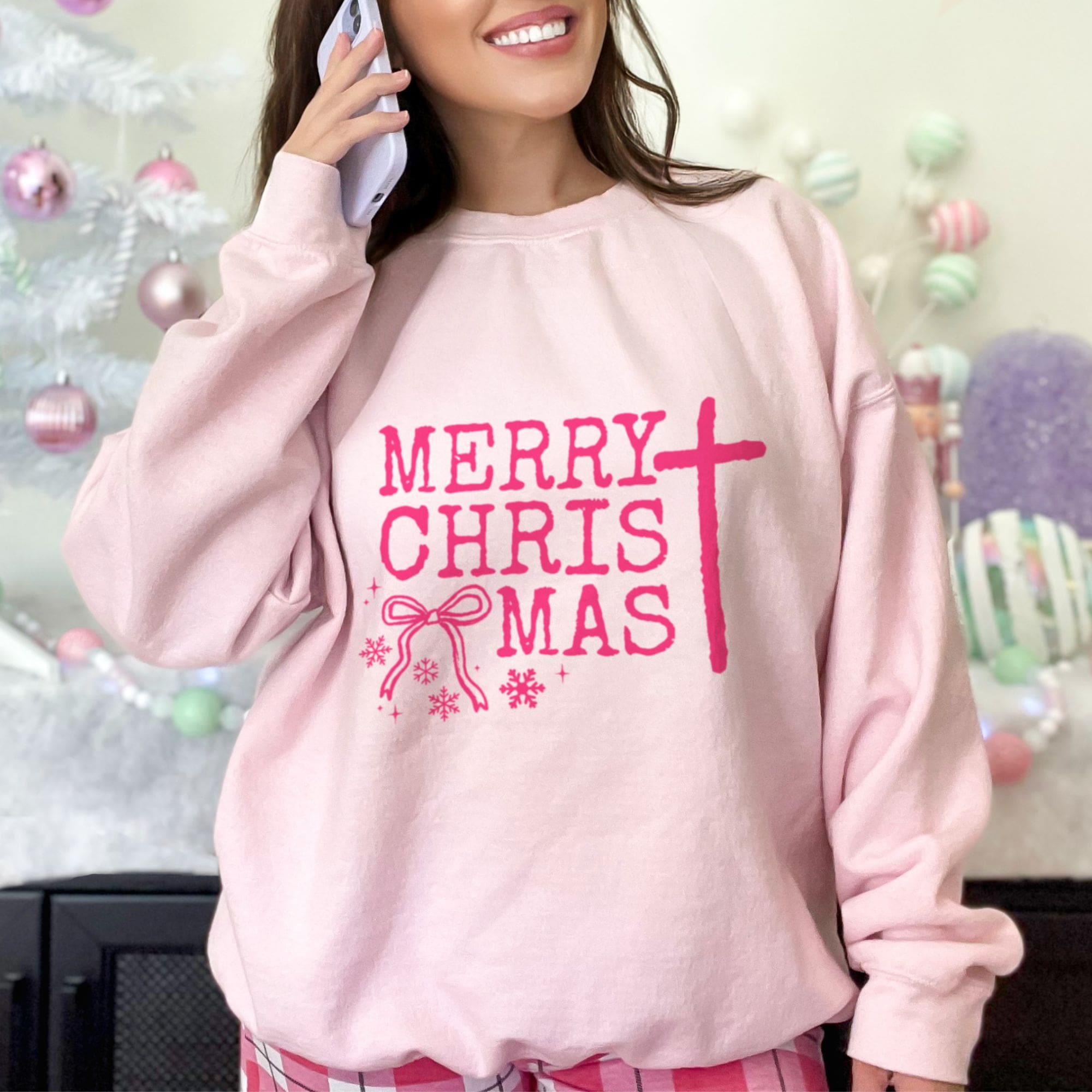 Person wearing a pink faith 'Merry Christmas' sweatshirt with a festive background.