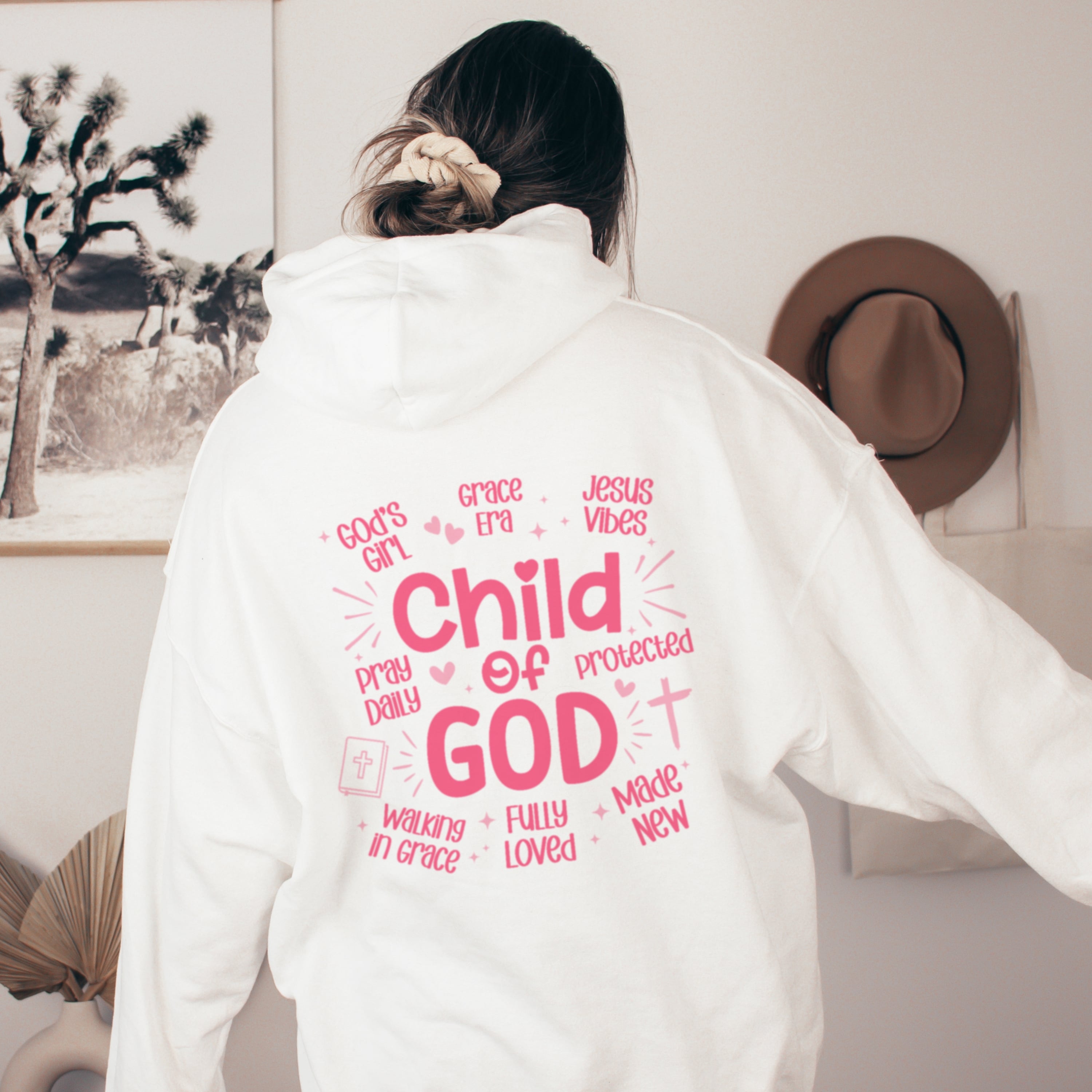 Woman wearing white Child of God hoodie with pink text