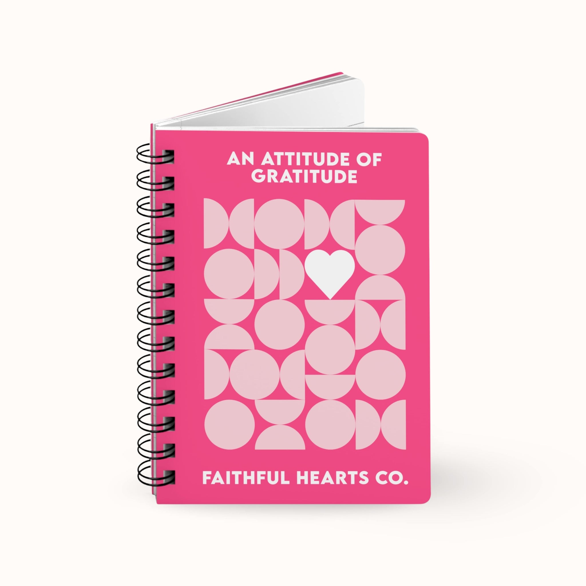 Pink gratitude notebook with geometric design and the text 'an attitude of gratitude' on a white background