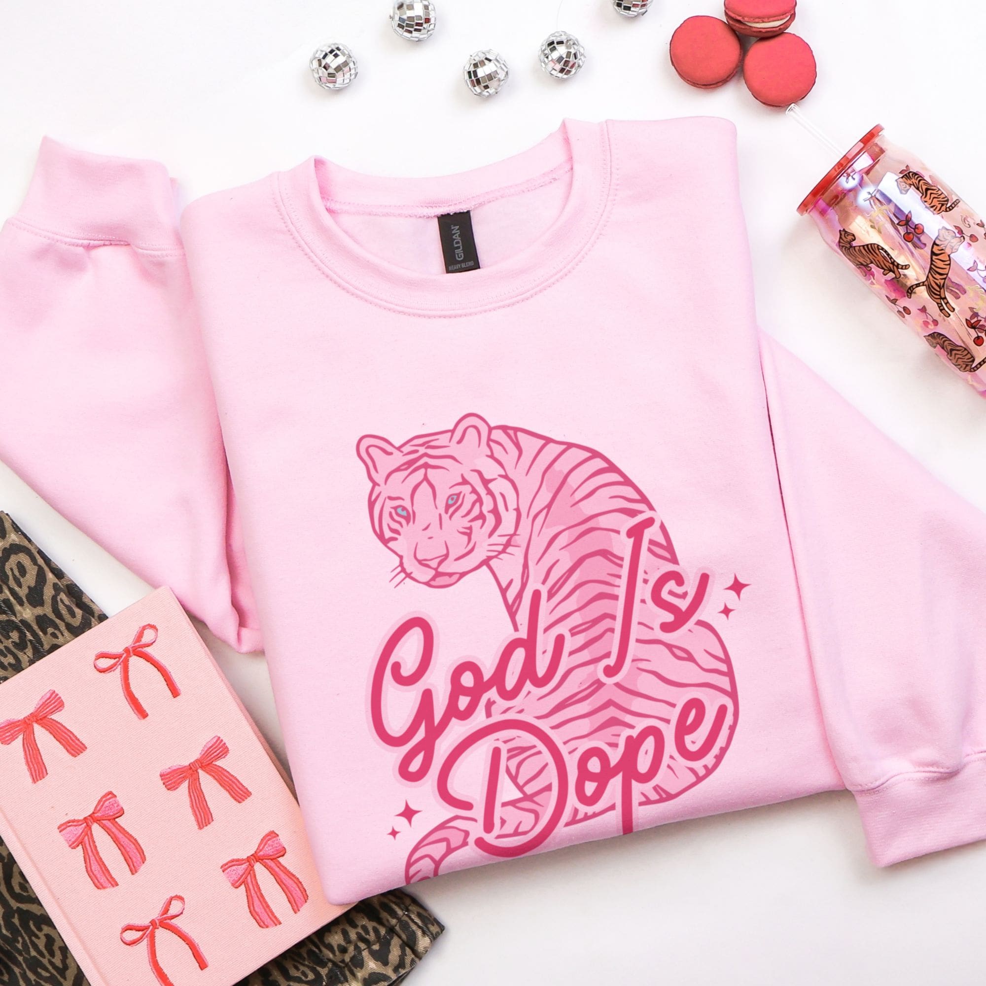 Pink sweatshirt with tiger graphic and 'God is Dope' text on a white background