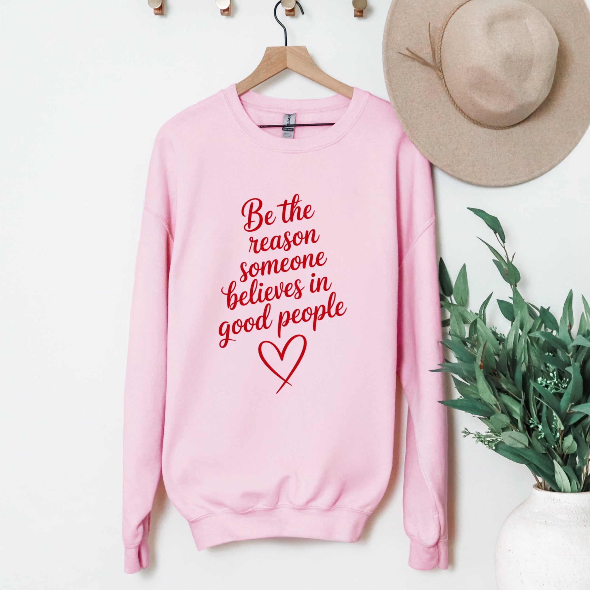Be The Reason Good People sweatshirt in pink hanging display - uplifting message crewneck clothing