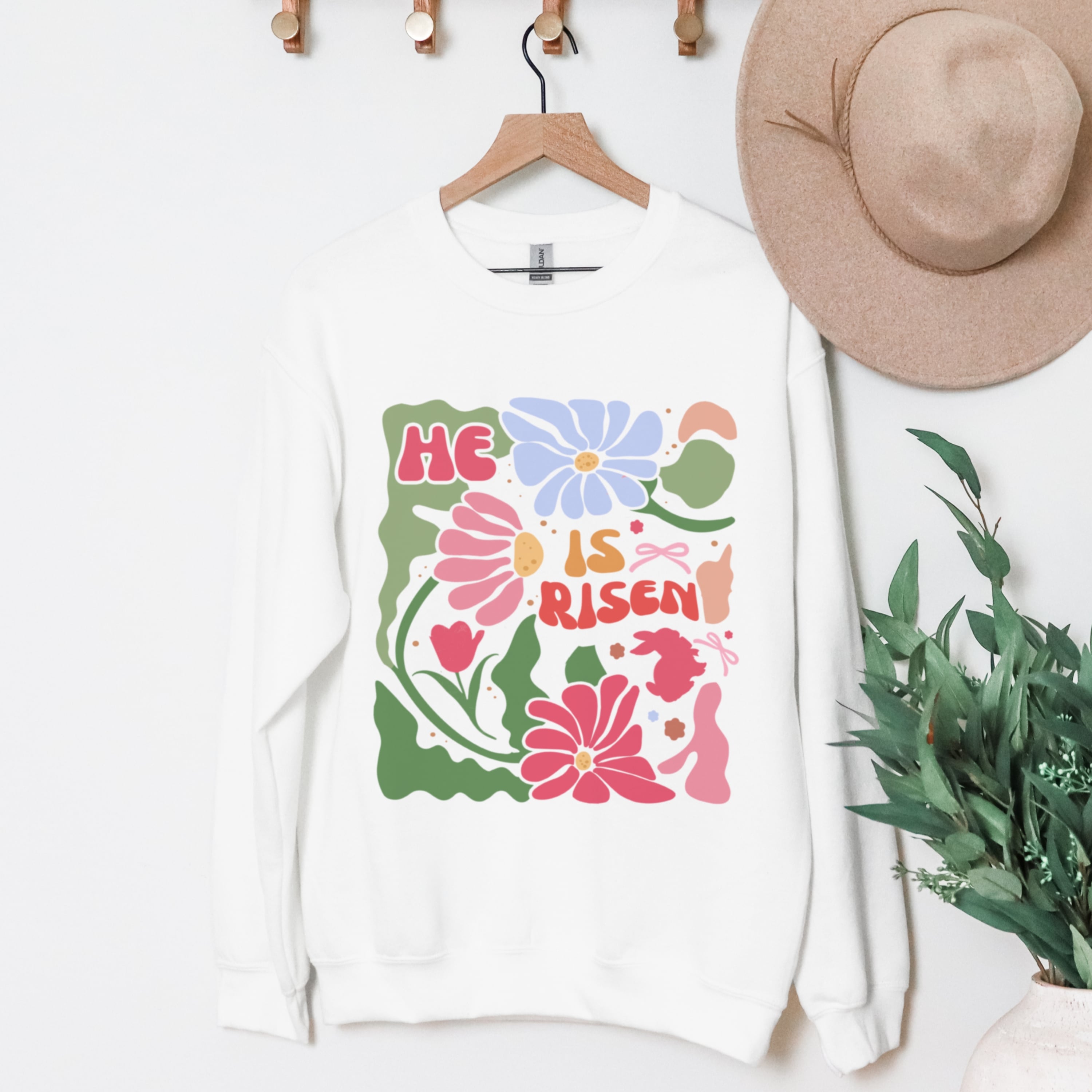 He Is Risen white sweatshirt with retro flowers hanging display - vintage Christian crewneck clothing