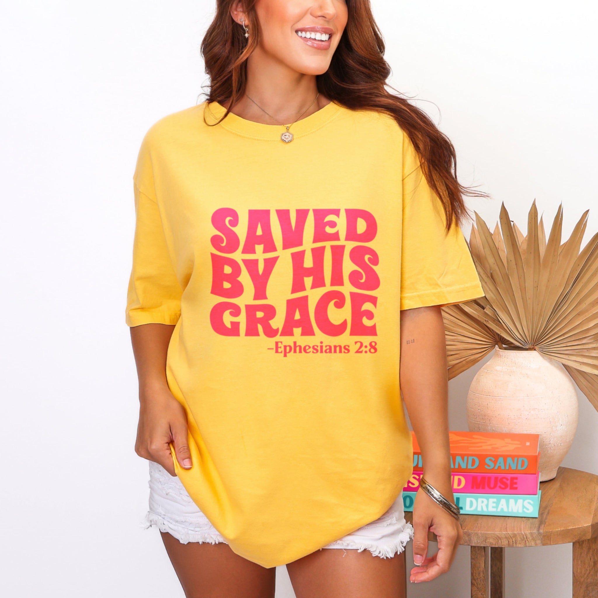 Woman wearing bright citrus yellow Saved By His Grace tshirt with hot pink Ephesians 2:8, trendy Christian faith graphic tee