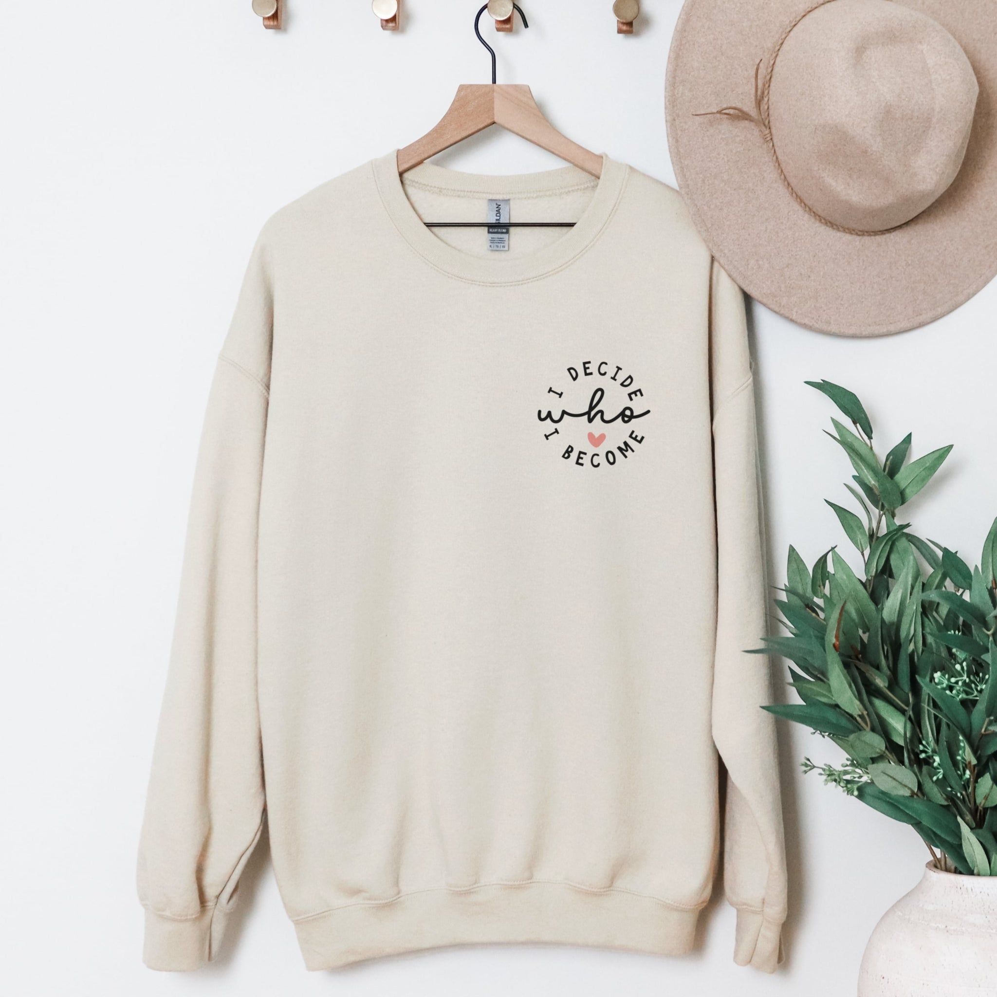 Beige I Decide Who I Become chest print sweatshirt on a clothes hanger