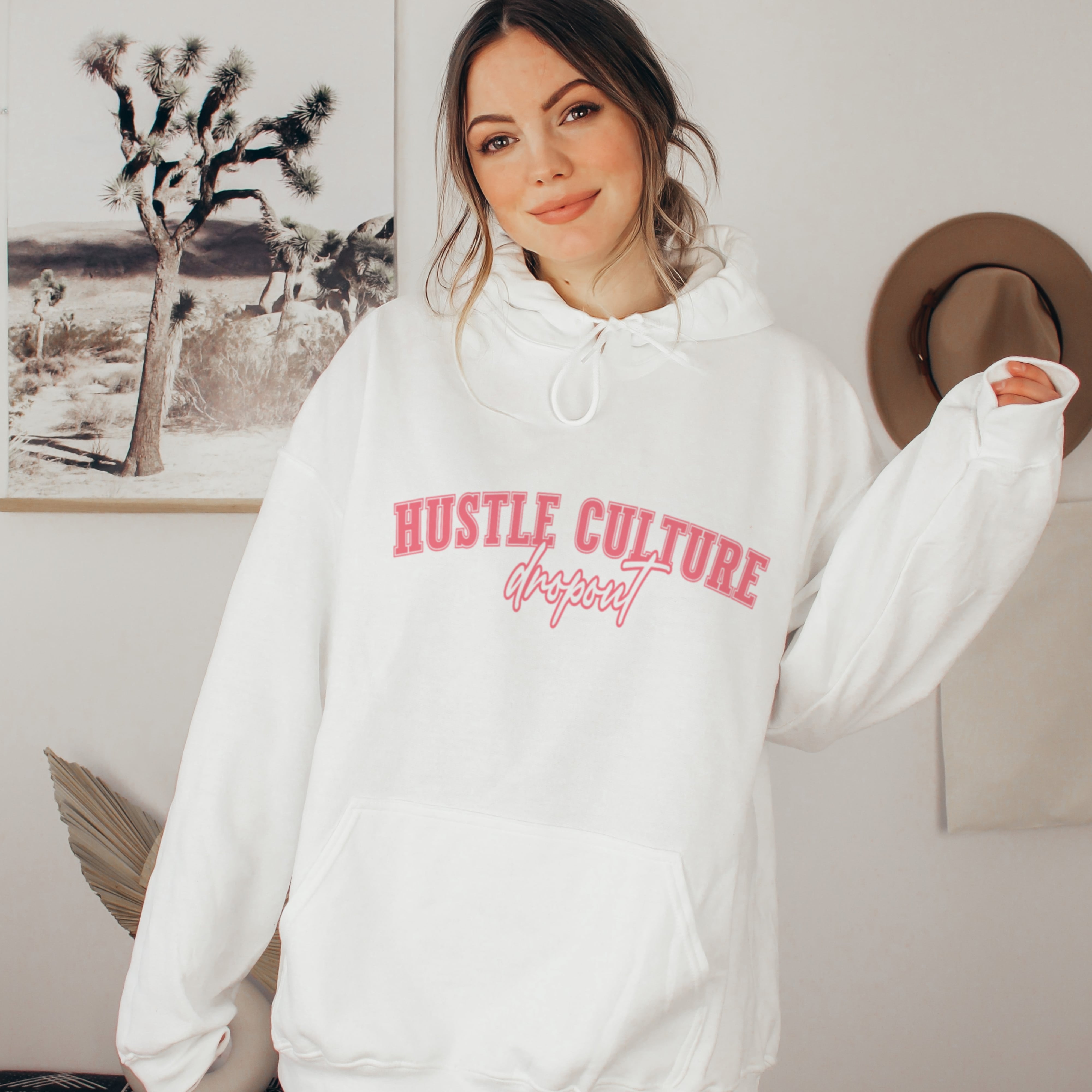 Woman in white hustle culture dropout hoodie, cozy anti-grind soft life