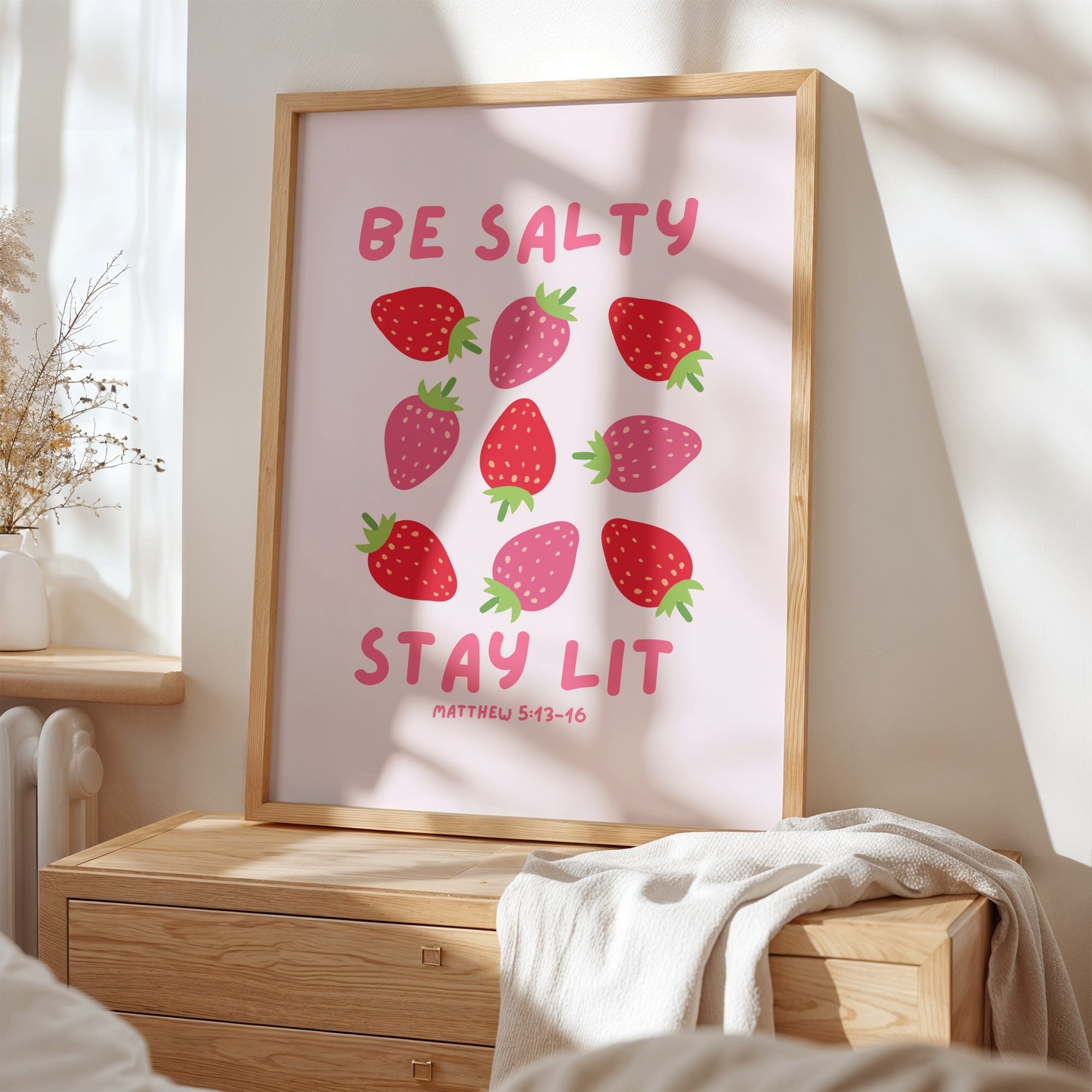 Framed poster with strawberry design and text 'Be Salty Stay Lit' on a wall.