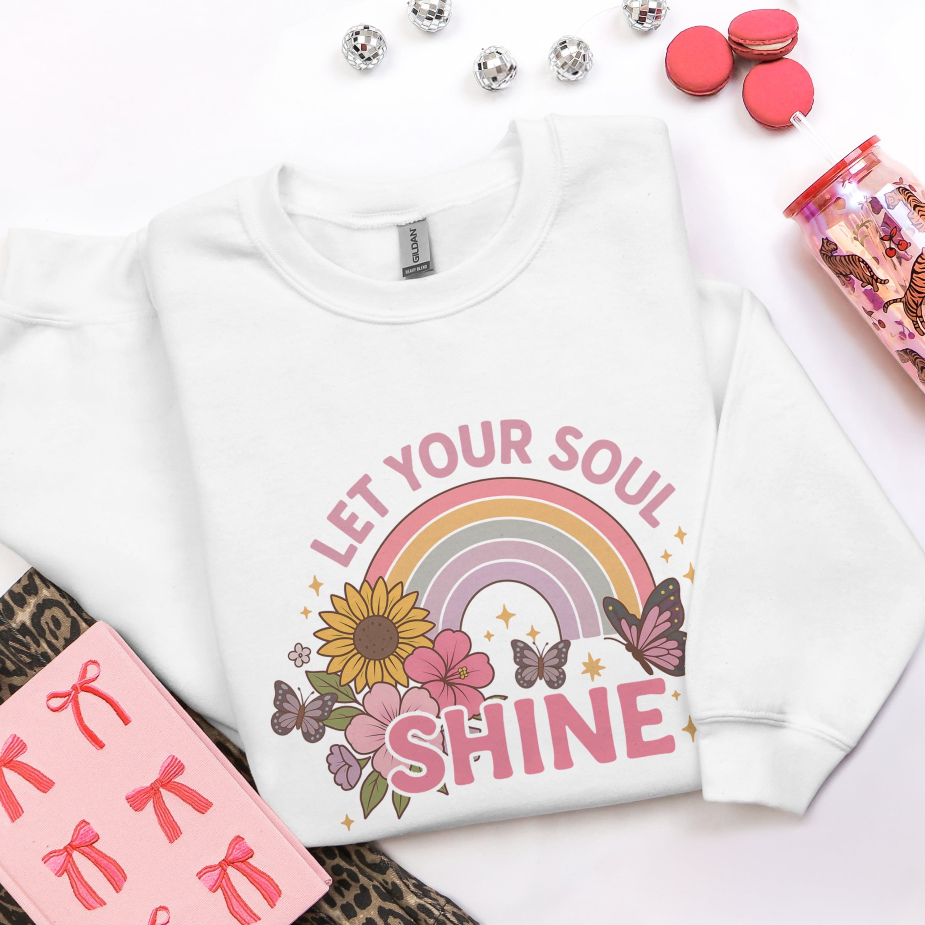 Let Your Soul Shine white sweatshirt flat lay with rainbow floral butterfly design - positive Christian faith apparel