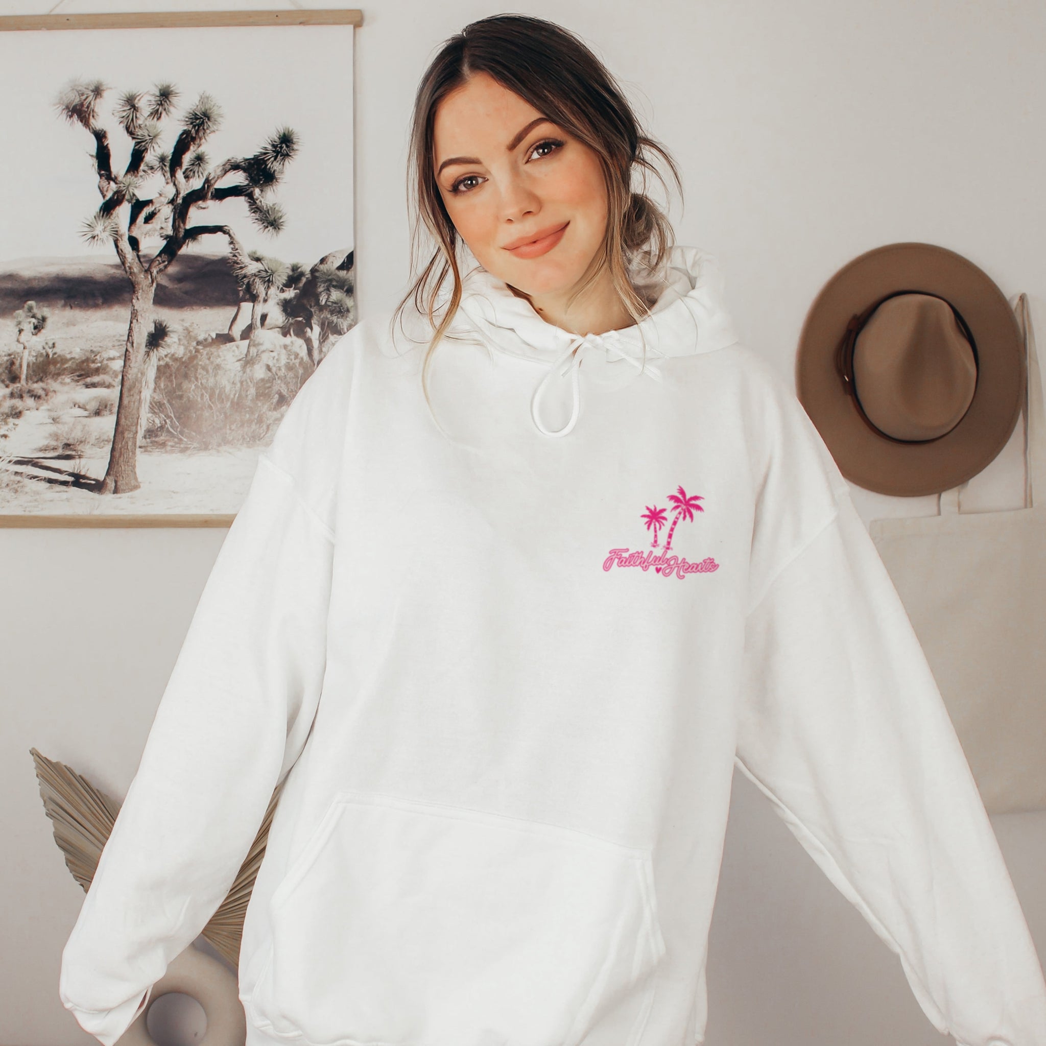 Woman wearing white Faithful Hearts hoodie with palm tree logo, faith-based brand sweatshirt for women